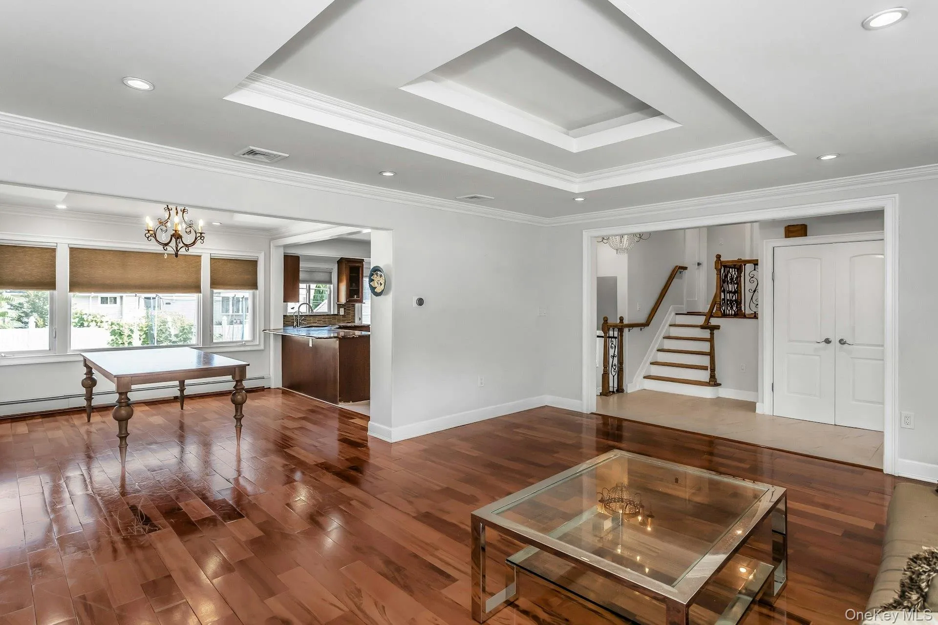 Living area featuring a chandelier, recessed lighting, a tray ceiling, wood finished floors, and ornamental molding Living area featuring a chandelier, recessed lighting, a tray ceiling, wood finished floors, and ornamental molding