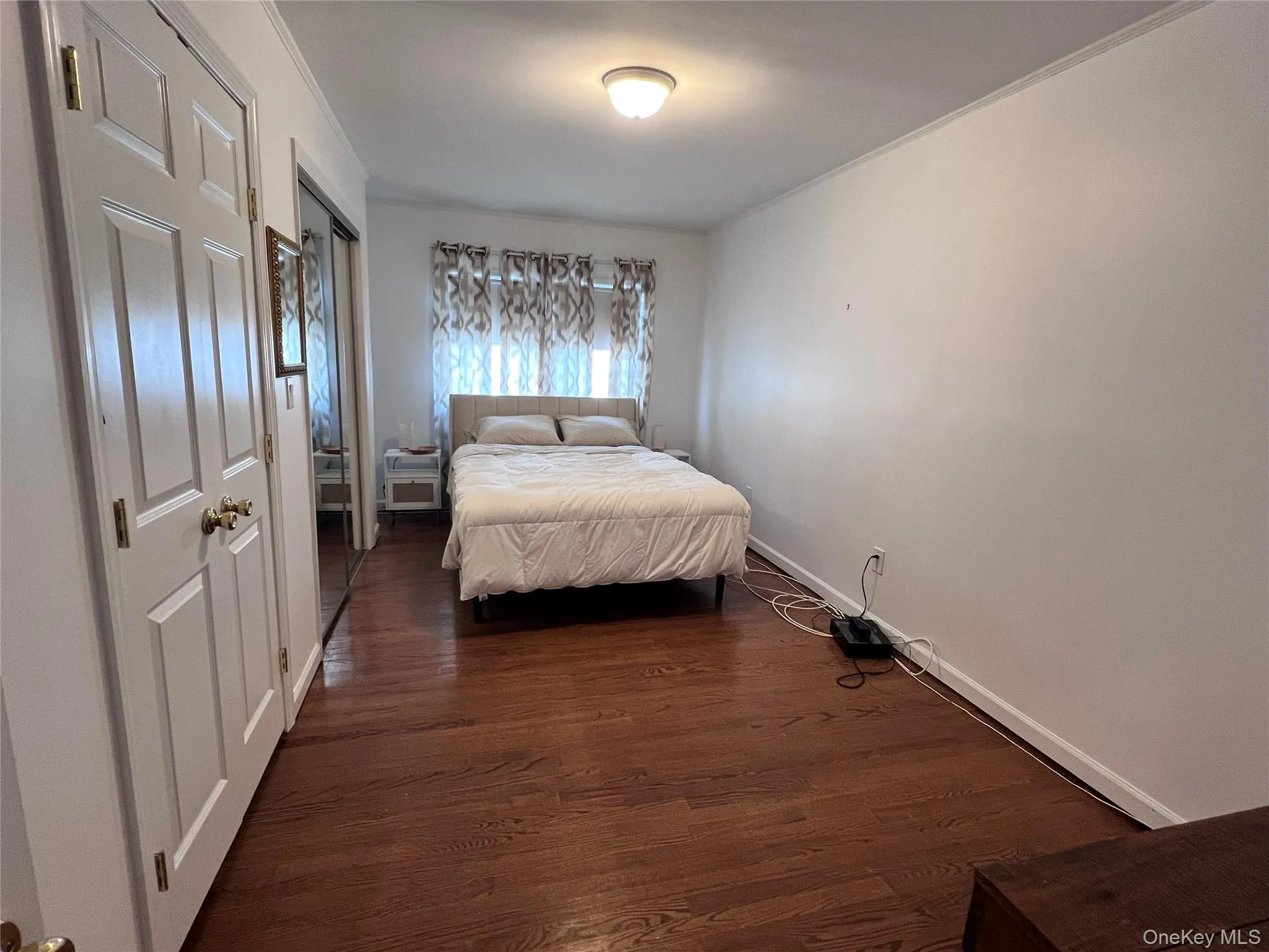 Bedroom with baseboards, dark wood-type flooring, and ornamental molding Bedroom with baseboards, dark wood-type flooring, and ornamental molding