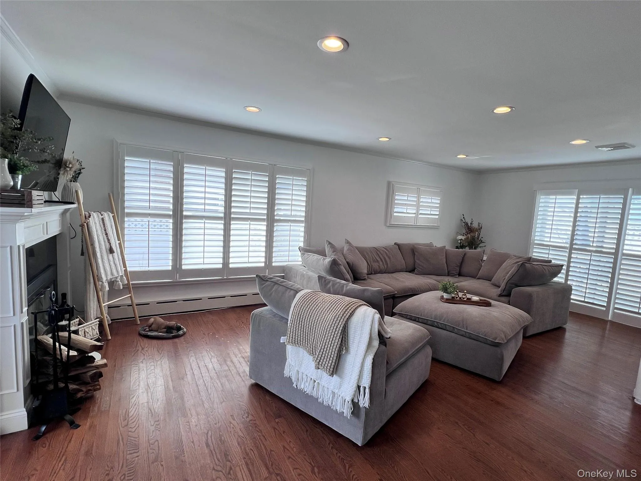 Living area featuring visible vents, a glass covered fireplace, dark wood-style floors, a baseboard heating unit, and recessed lighting Living area featuring visible vents, a glass covered fireplace, dark wood-style floors, a baseboard heating unit, and recessed lighting