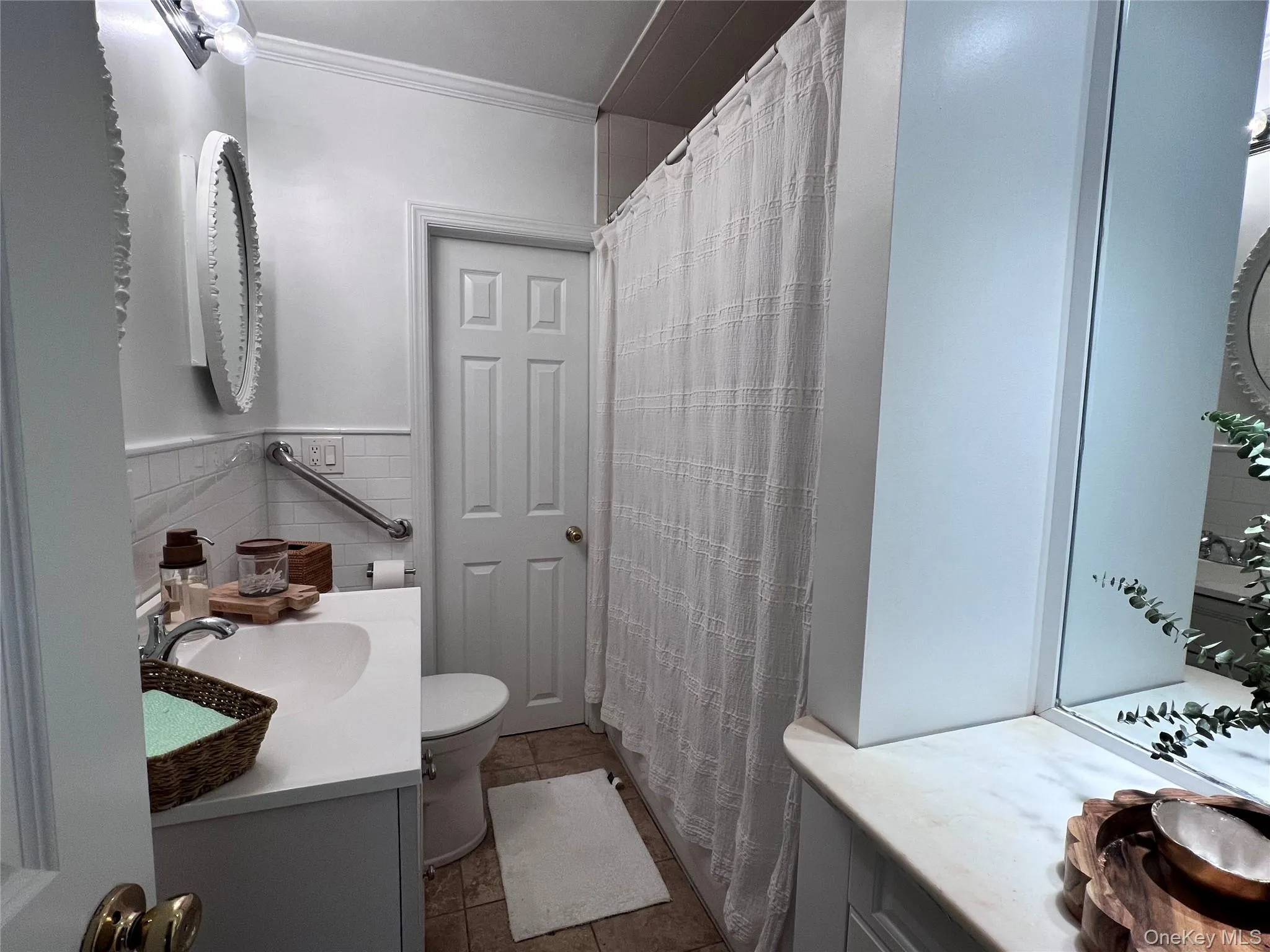 Full bath with crown molding, tile walls, toilet, vanity, and tile patterned flooring Full bath with crown molding, tile walls, toilet, vanity, and tile patterned flooring