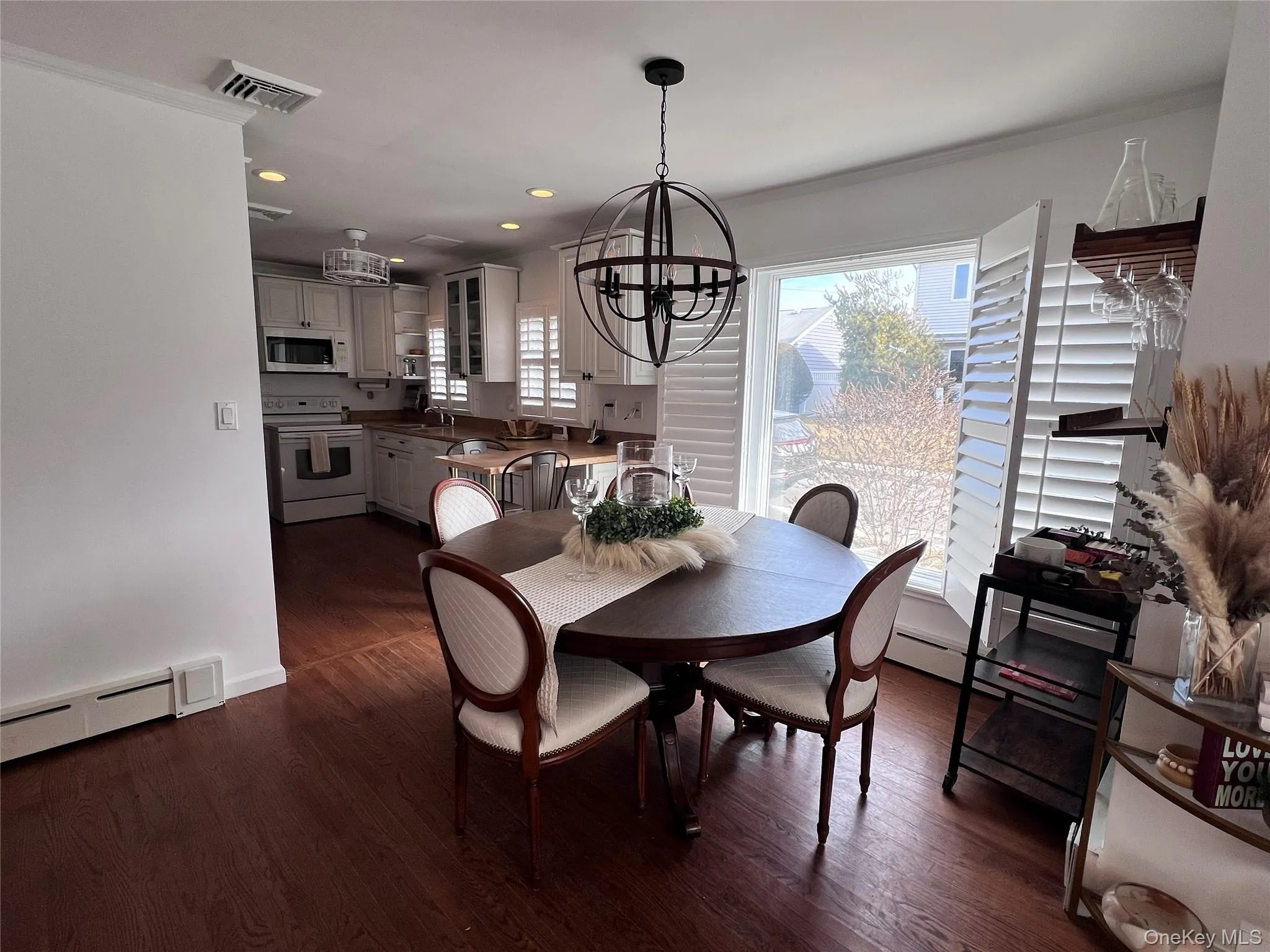 Dining space featuring a chandelier, visible vents, dark wood finished floors, and baseboard heating Dining space featuring a chandelier, visible vents, dark wood finished floors, and baseboard heating
