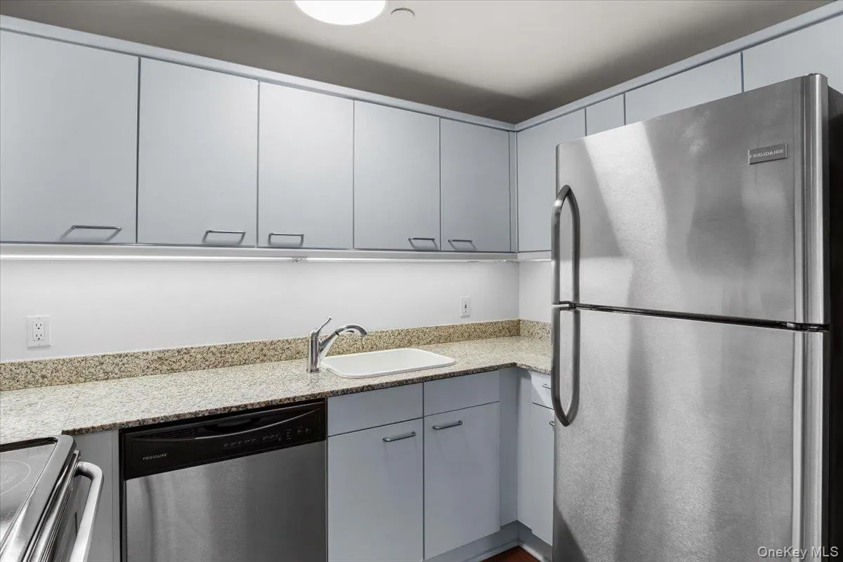 Kitchen featuring appliances with stainless steel finishes, gray cabinets, and light stone counters Kitchen featuring appliances with stainless steel finishes, gray cabinets, and light stone counters