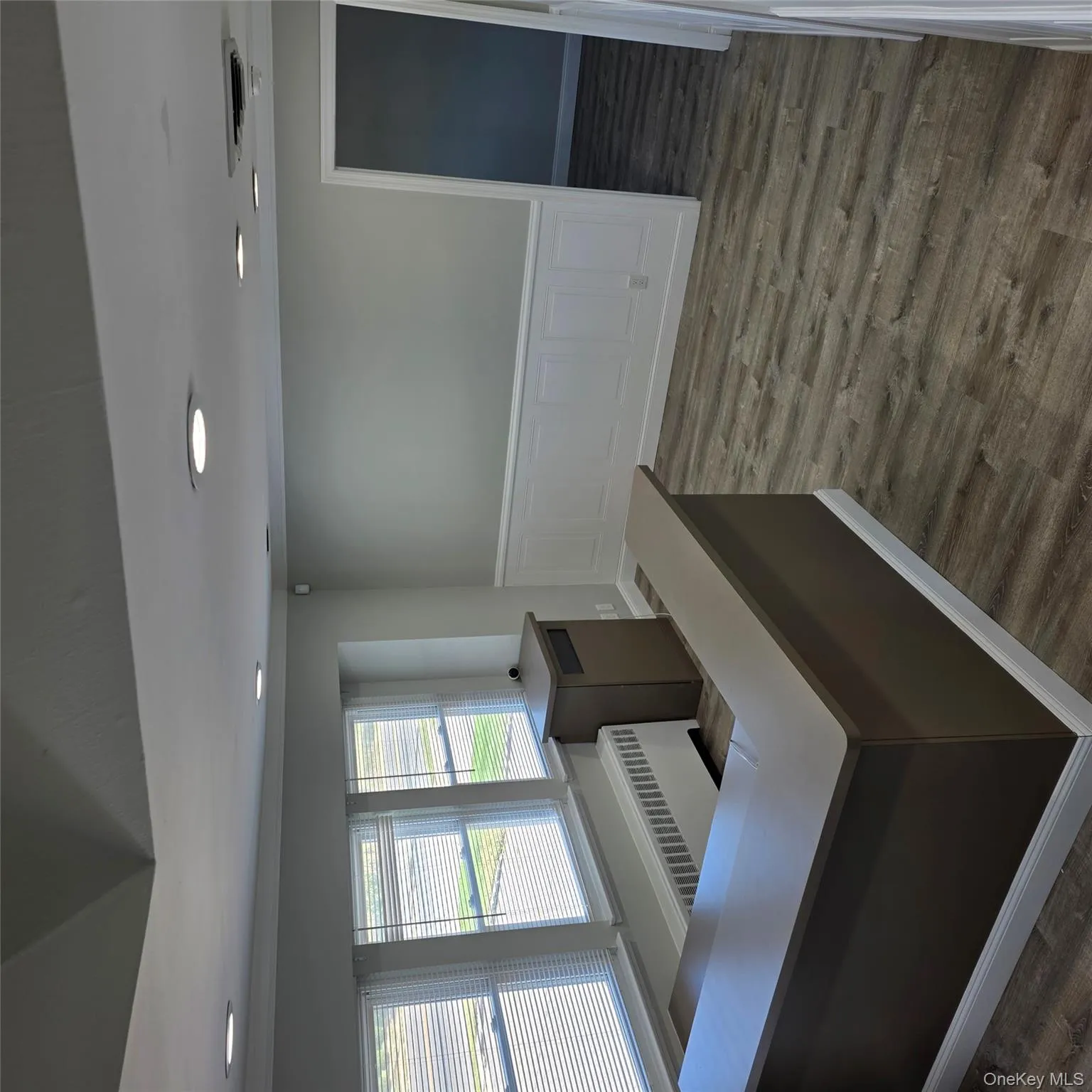 Office space with recessed lighting, wood finished floors, radiator, wainscoting, and a decorative wall Office space with recessed lighting, wood finished floors, radiator, wainscoting, and a decorative wall