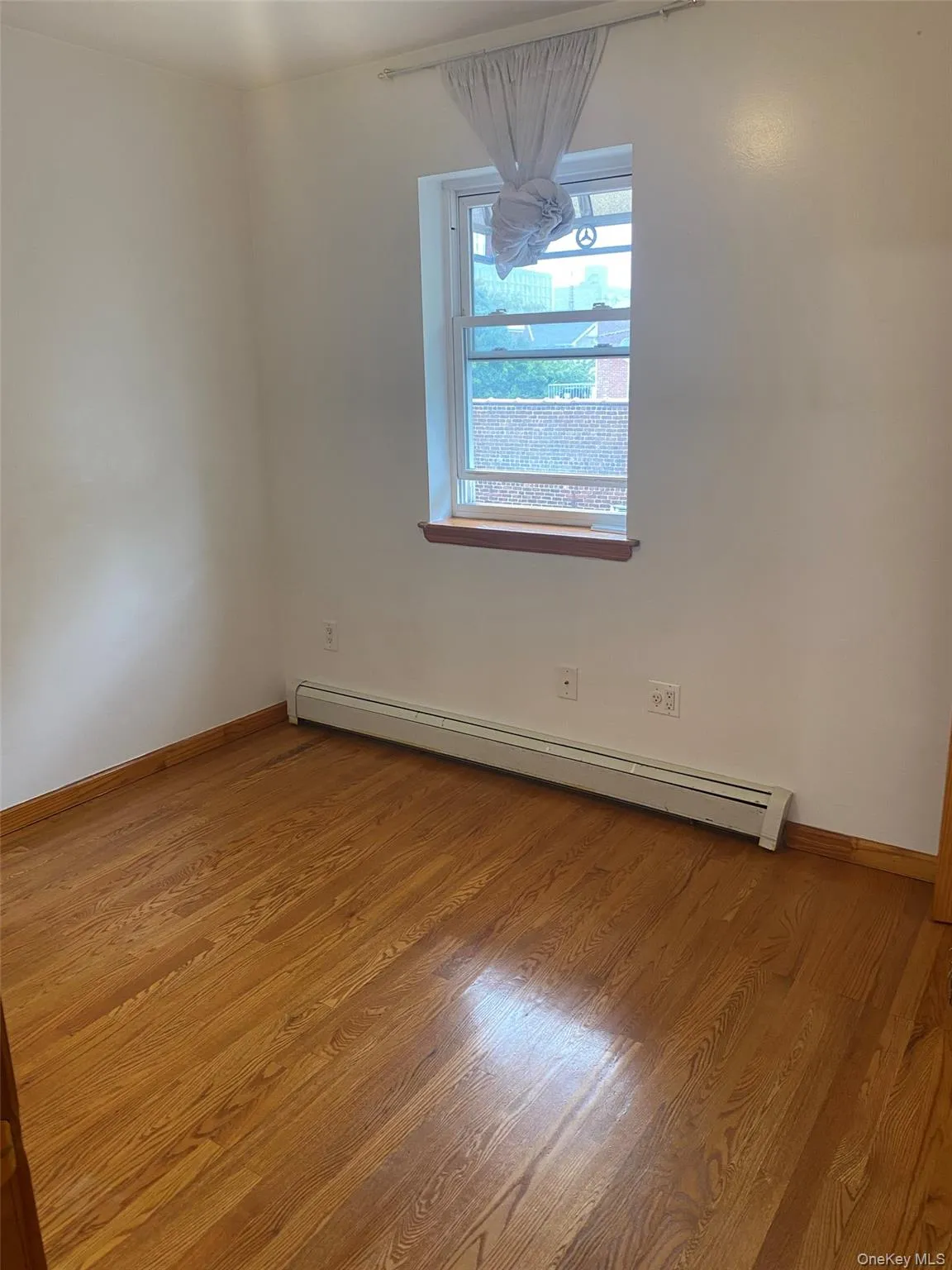 Empty room with a baseboard heating unit and light wood-style floors Empty room with a baseboard heating unit and light wood-style floors