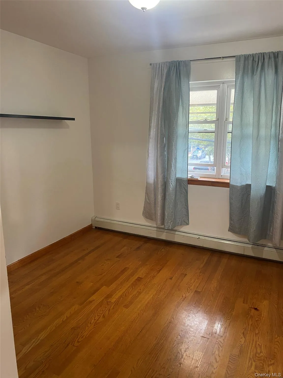 Empty room with baseboard heating and wood finished floors Empty room with baseboard heating and wood finished floors