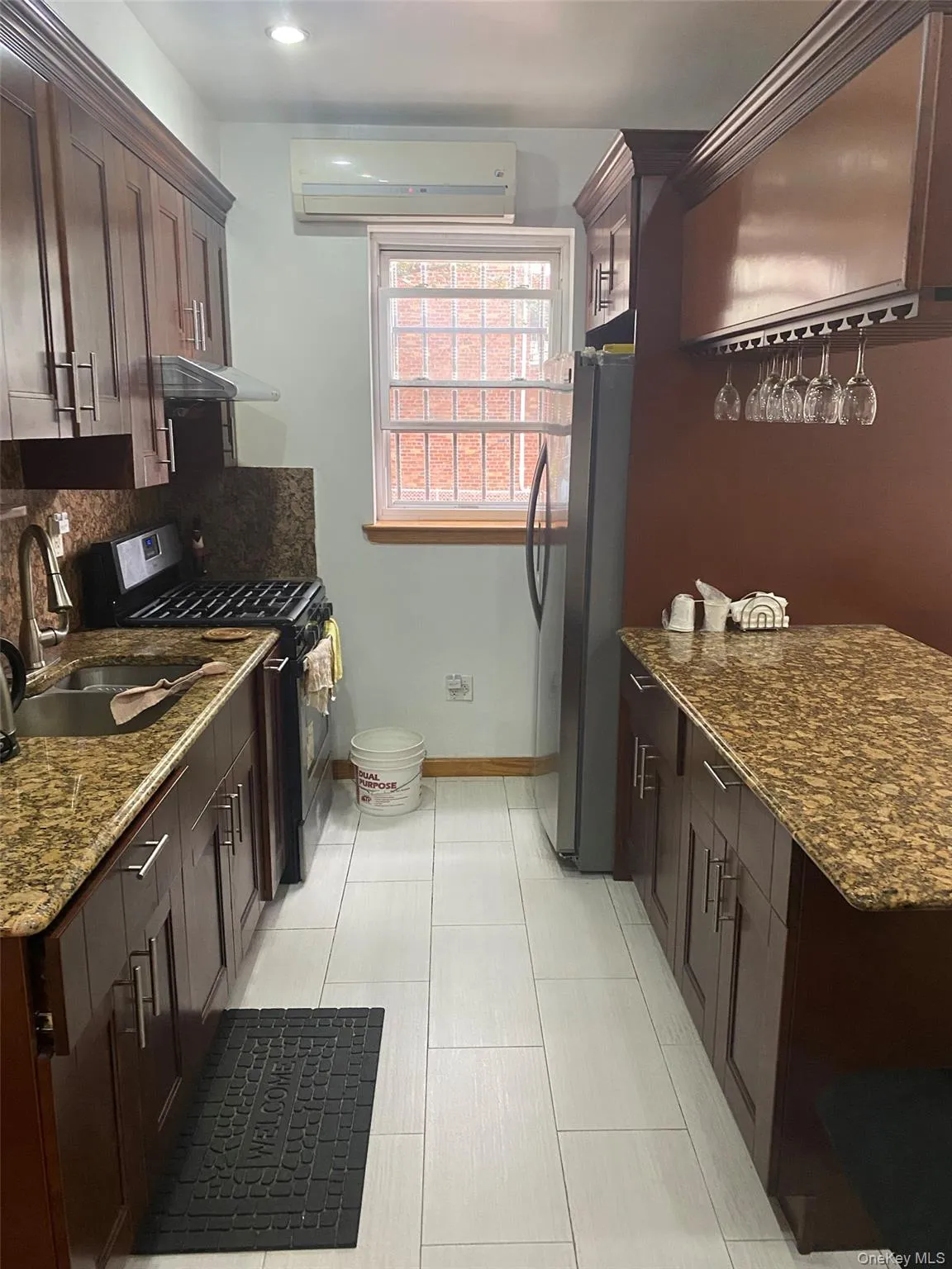Kitchen featuring dark stone countertops, dark brown cabinetry, appliances with stainless steel finishes, and backsplash Kitchen featuring dark stone countertops, dark brown cabinetry, appliances with stainless steel finishes, and backsplash