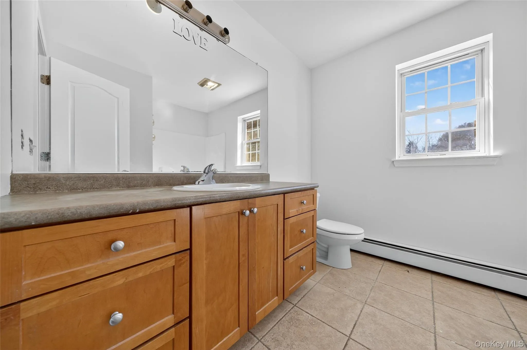 Bathroom with vanity, light tile patterned floors, and a baseboard radiator Bathroom with vanity, light tile patterned floors, and a baseboard radiator