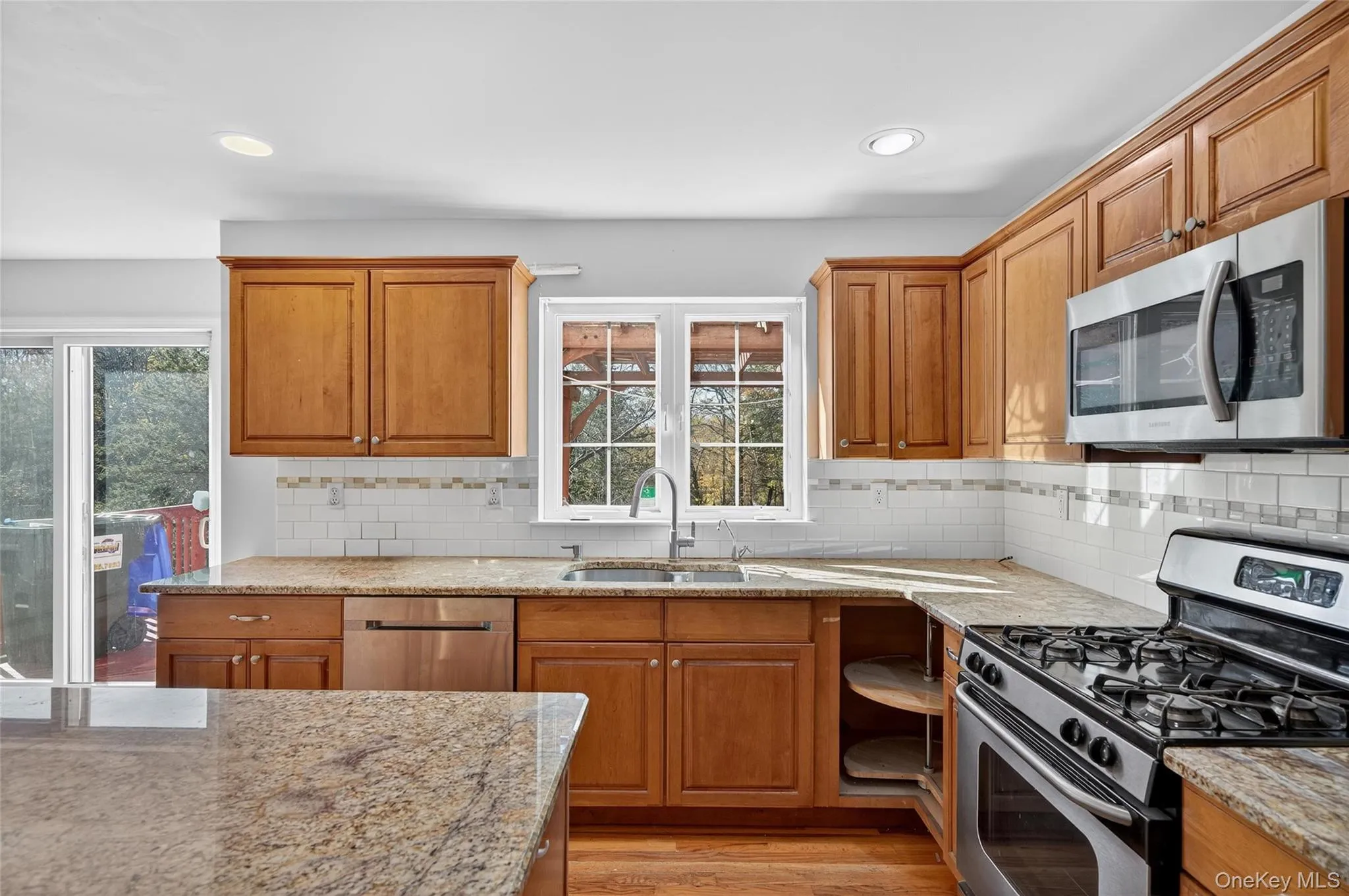 Kitchen with stainless steel appliances, brown cabinets, light stone counters, and recessed lighting Kitchen with stainless steel appliances, brown cabinets, light stone counters, and recessed lighting