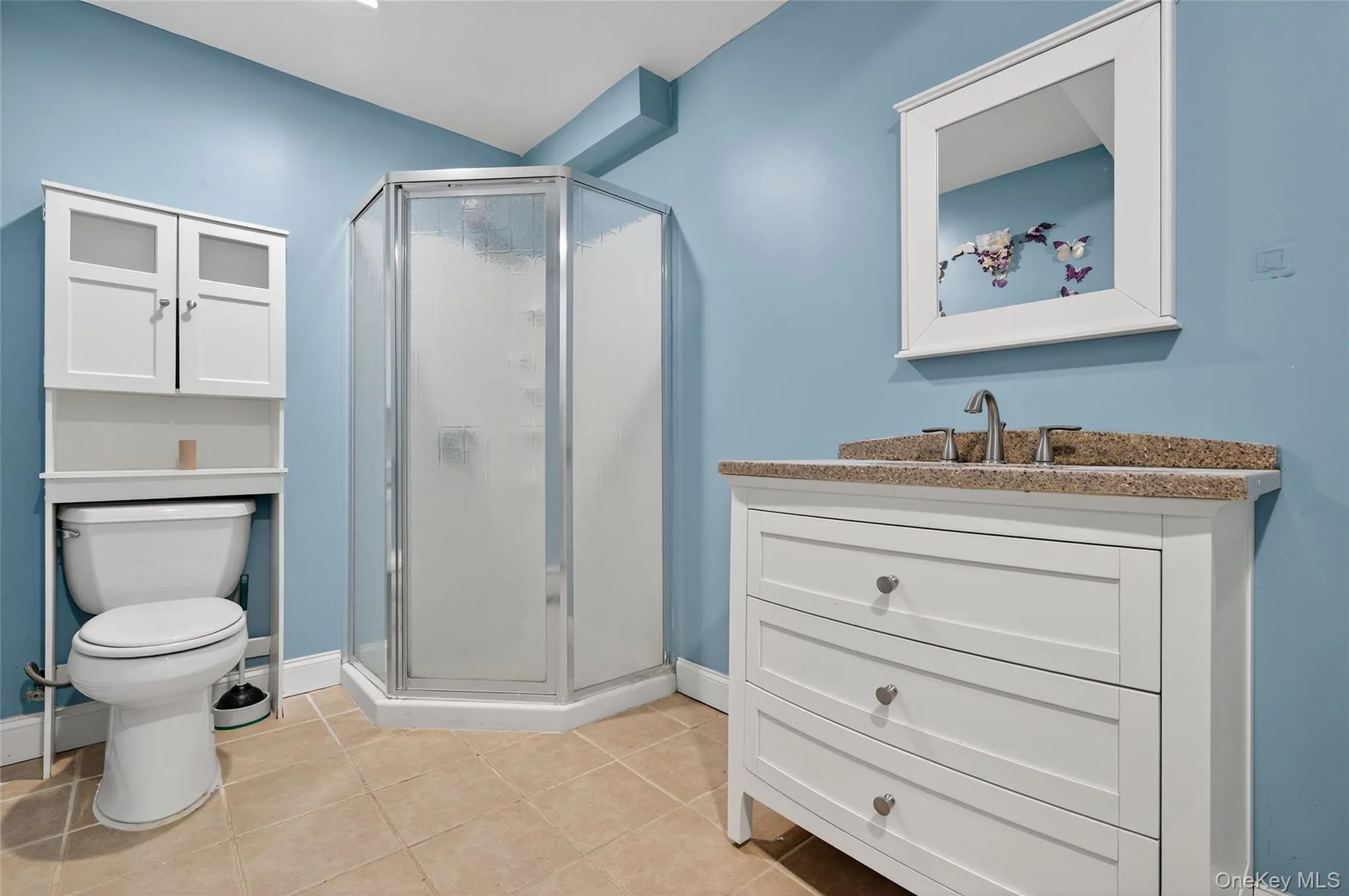 Full bath with vanity, a stall shower, and light tile patterned floors Full bath with vanity, a stall shower, and light tile patterned floors