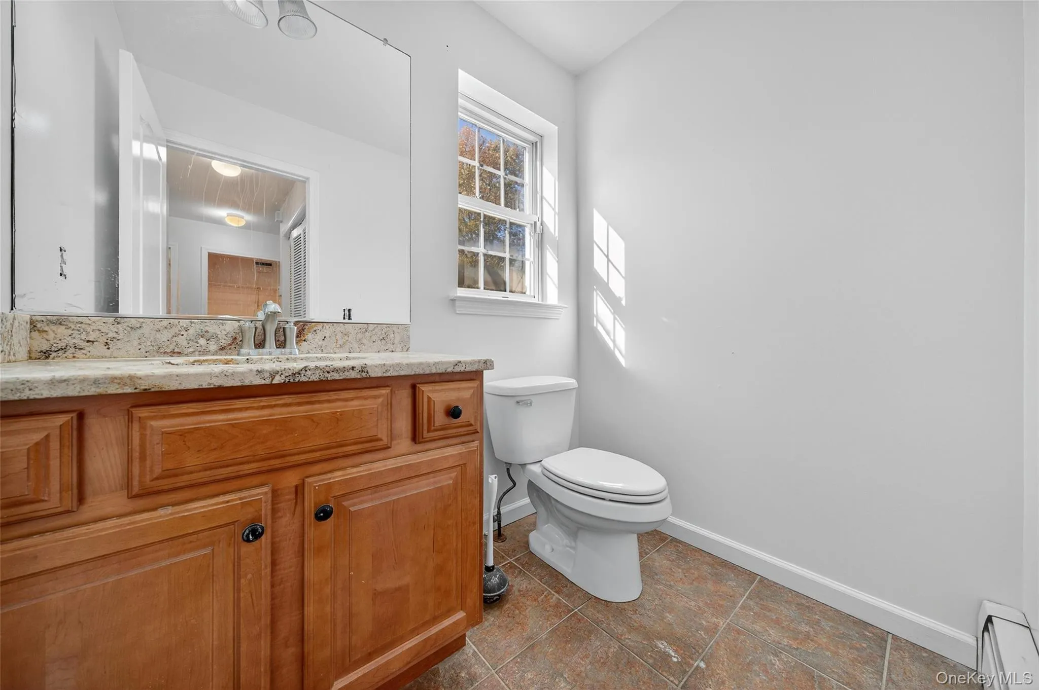 Half bathroom featuring vanity, a baseboard radiator, and dark tile patterned floors Half bathroom featuring vanity, a baseboard radiator, and dark tile patterned floors