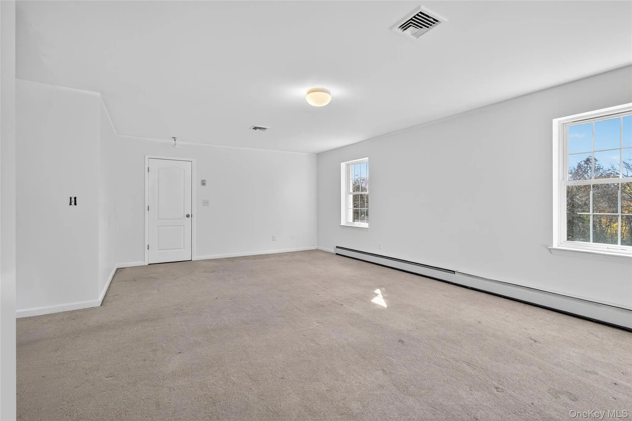 Empty room featuring baseboard heating and light colored carpet Empty room featuring baseboard heating and light colored carpet