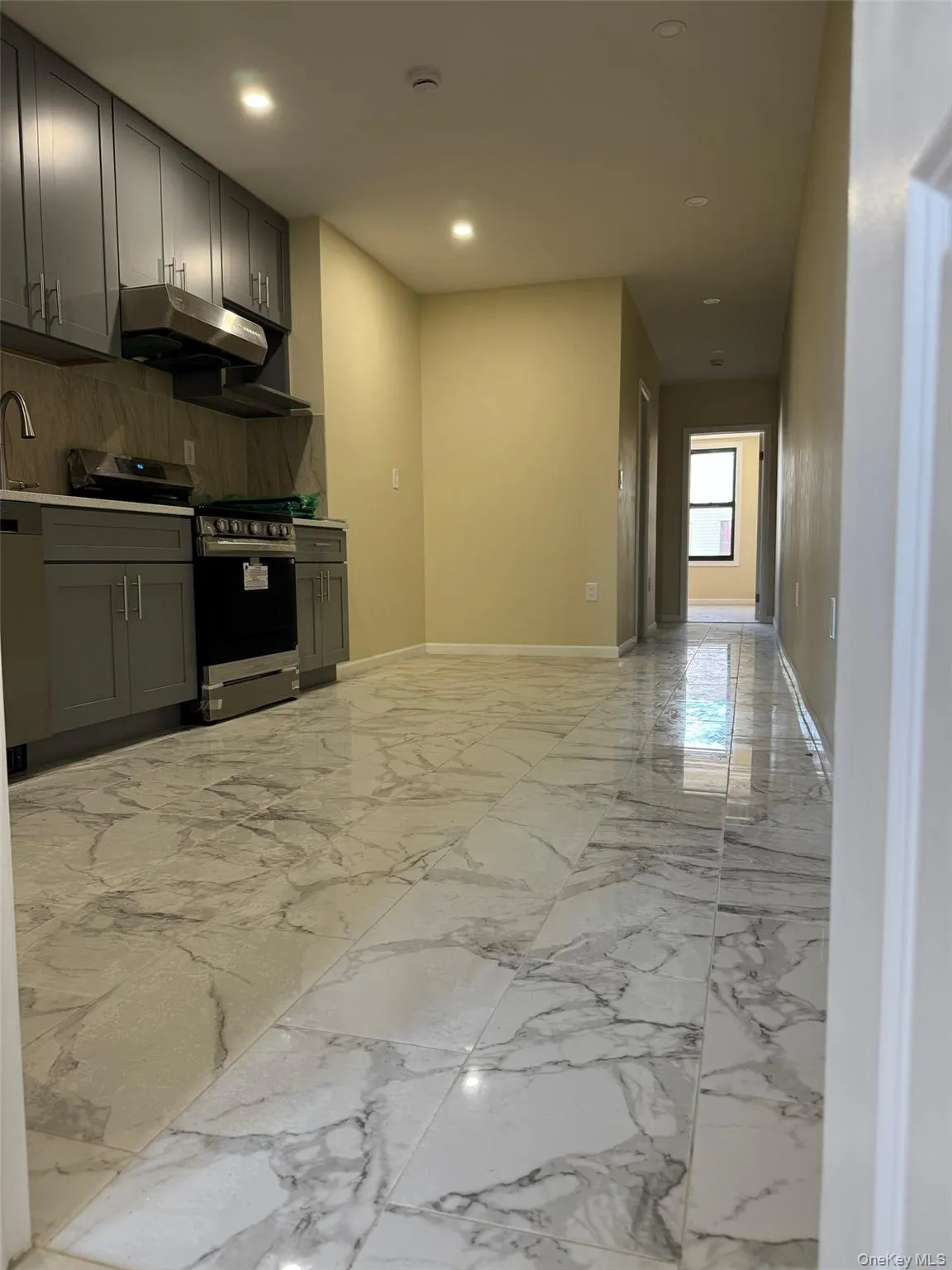 Kitchen with gray cabinetry, light marble finish flooring, stainless steel range with gas cooktop, decorative backsplash, and recessed lighting Kitchen with gray cabinetry, light marble finish flooring, stainless steel range with gas cooktop, decorative backsplash, and recessed lighting