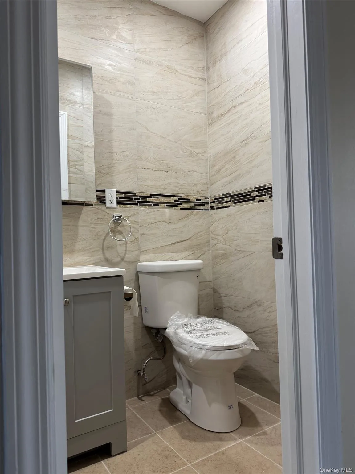Half bath featuring light tile patterned flooring, vanity, and tile walls Half bath featuring light tile patterned flooring, vanity, and tile walls