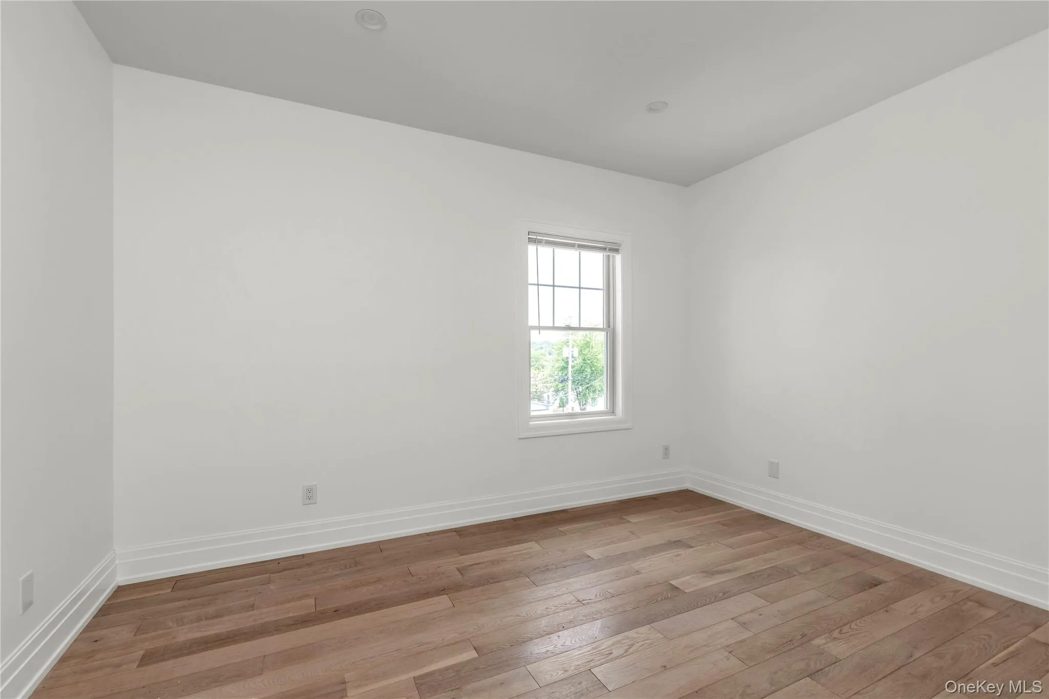 Spare room with light wood-style floors and baseboards Spare room with light wood-style floors and baseboards