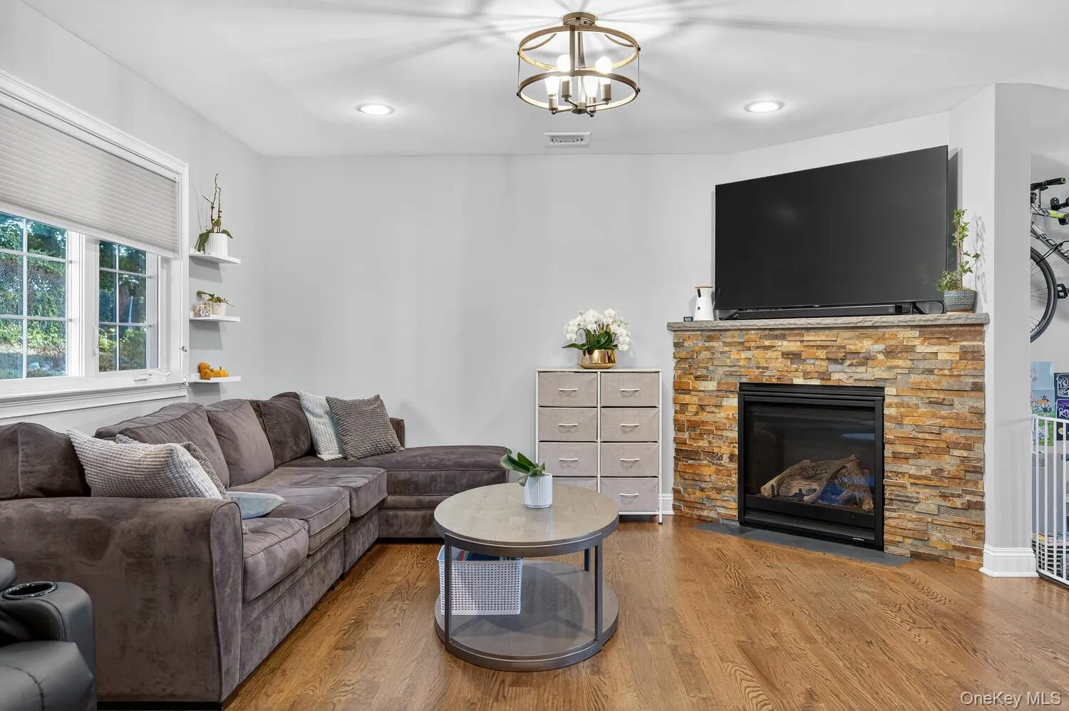 Living area with wood finished floors, a stone fireplace, recessed lighting, and a chandelier Living area with wood finished floors, a stone fireplace, recessed lighting, and a chandelier