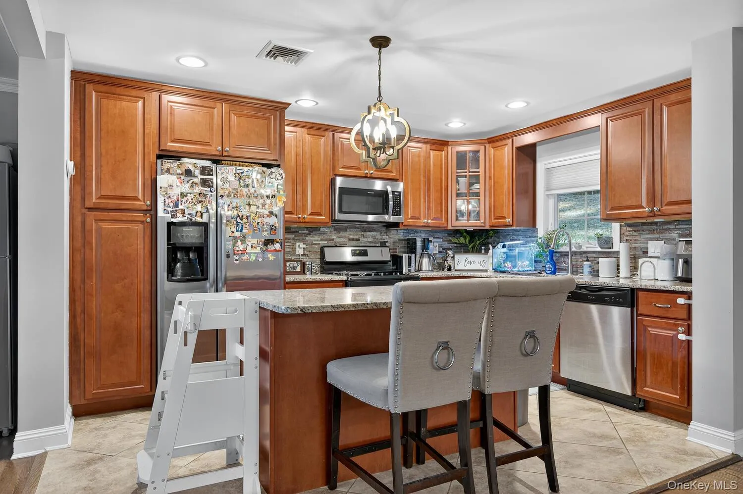Kitchen with a breakfast bar, brown cabinetry, light stone countertops, and recessed lighting Kitchen with a breakfast bar, brown cabinetry, light stone countertops, and recessed lighting