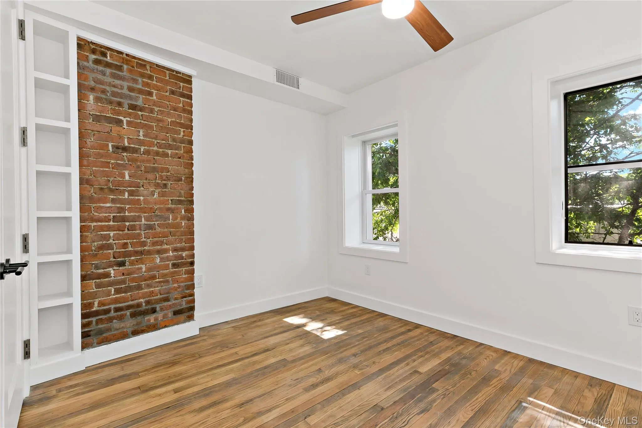 Bedroom with brick accent wall, ceiling fan and built in shelving Bedroom with brick accent wall, ceiling fan and built in shelving