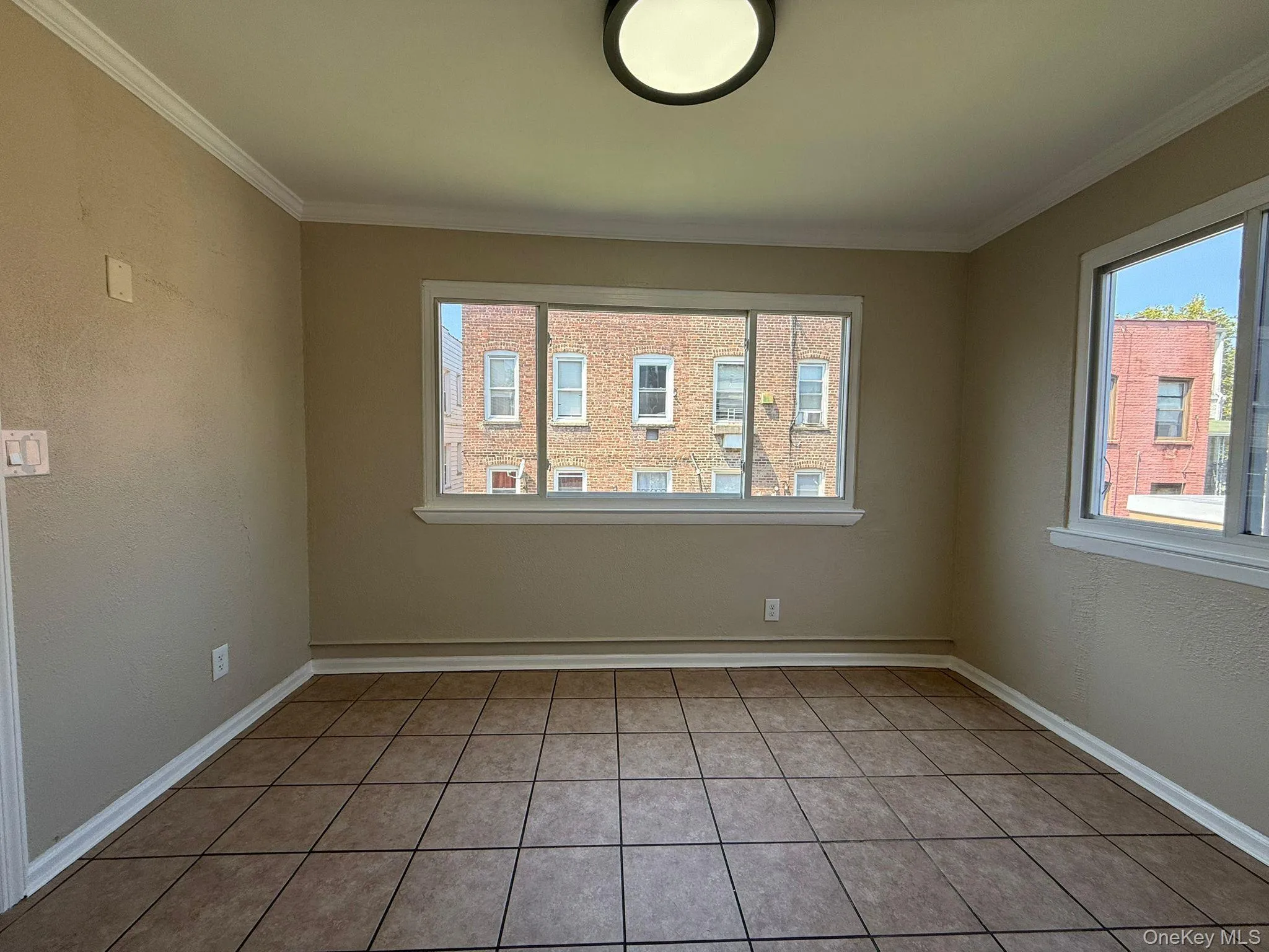 Spare room featuring a textured wall, ornamental molding, and light tile patterned floors Spare room featuring a textured wall, ornamental molding, and light tile patterned floors