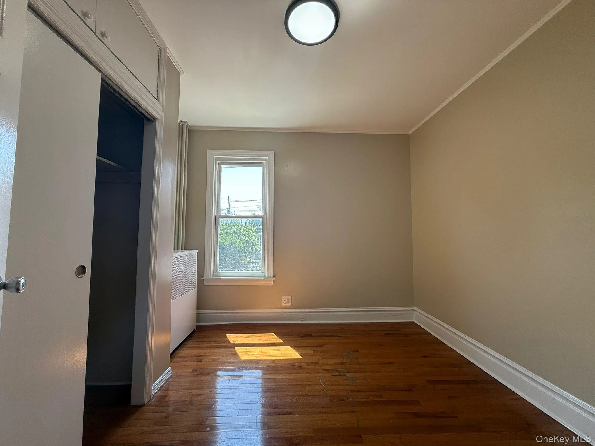 Unfurnished bedroom with dark wood-type flooring, crown molding, and a closet Unfurnished bedroom with dark wood-type flooring, crown molding, and a closet