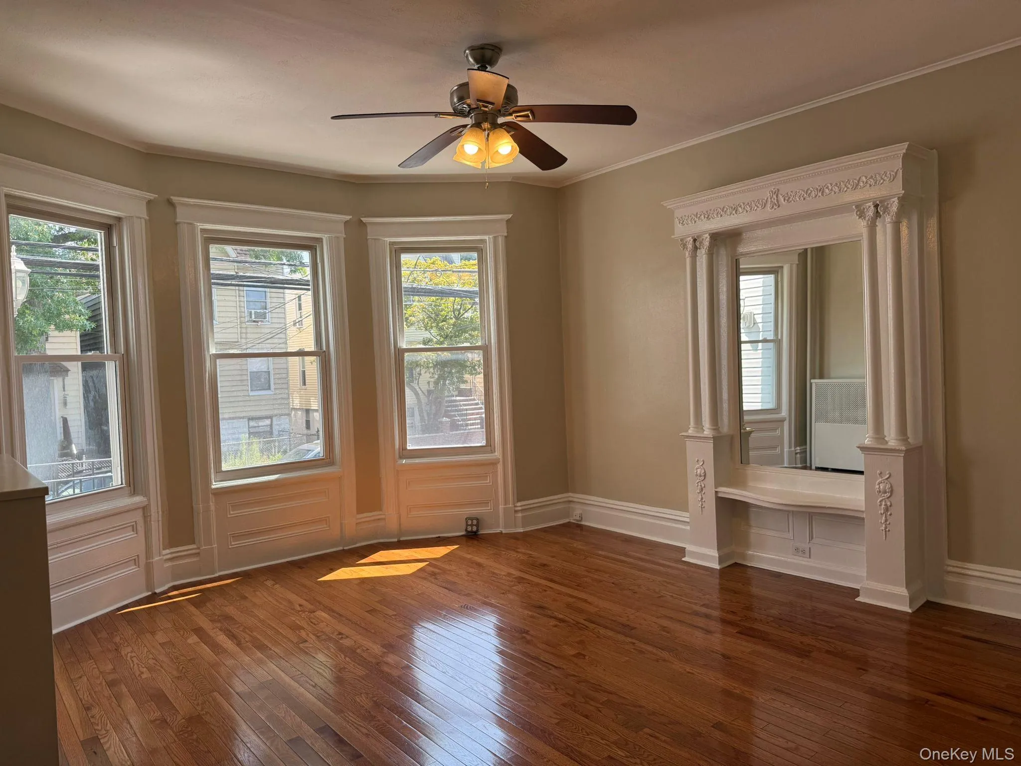 Doorway to outside featuring hardwood / wood-style floors, ornamental molding, radiator heating unit, and a ceiling fan Doorway to outside featuring hardwood / wood-style floors, ornamental molding, radiator heating unit, and a ceiling fan