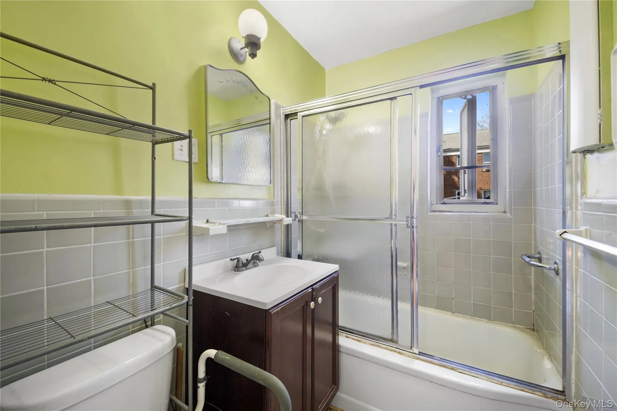 Bathroom featuring vanity, shower / bath combination with glass door, and tile walls Bathroom featuring vanity, shower / bath combination with glass door, and tile walls