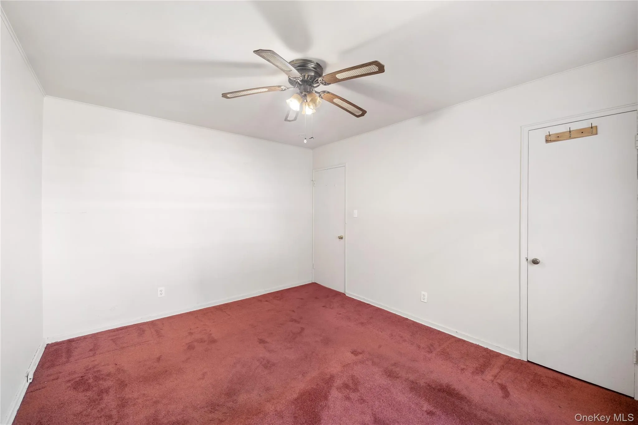 Carpeted spare room with a ceiling fan and baseboards Carpeted spare room with a ceiling fan and baseboards