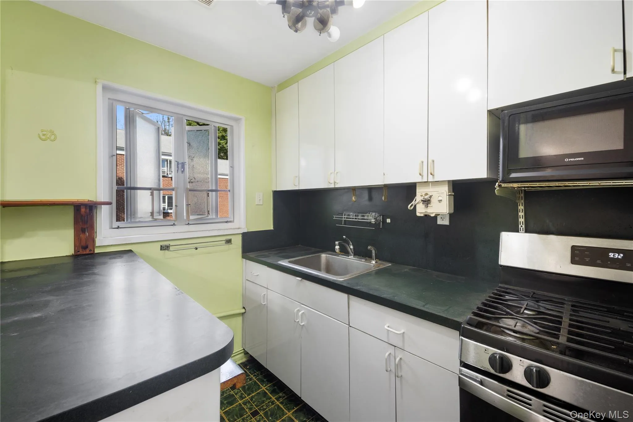 Kitchen with stainless steel gas range, dark countertops, white cabinets, black microwave, and decorative backsplash Kitchen with stainless steel gas range, dark countertops, white cabinets, black microwave, and decorative backsplash