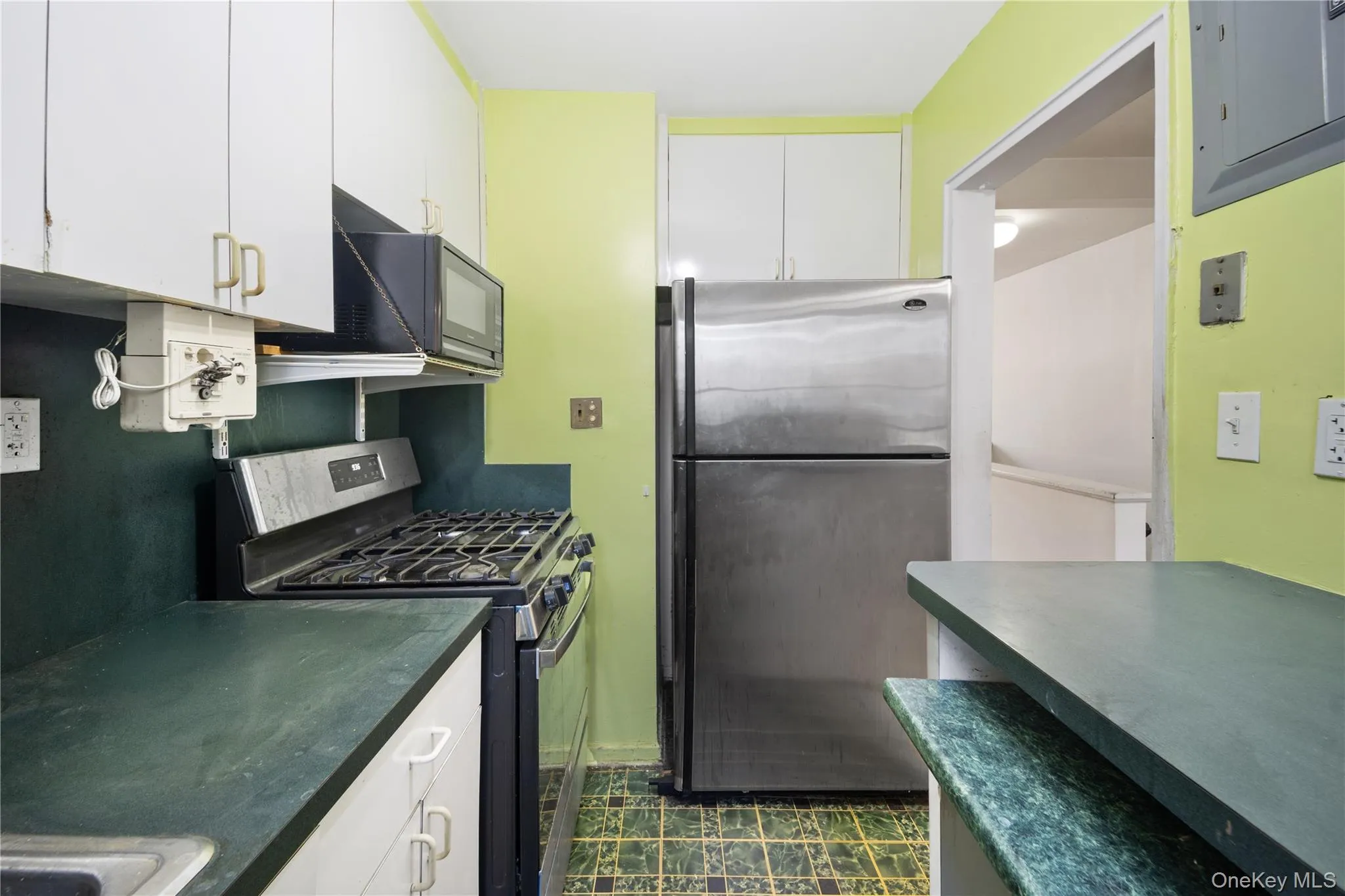 Kitchen featuring appliances with stainless steel finishes, white cabinets, electric panel, and dark countertops Kitchen featuring appliances with stainless steel finishes, white cabinets, electric panel, and dark countertops