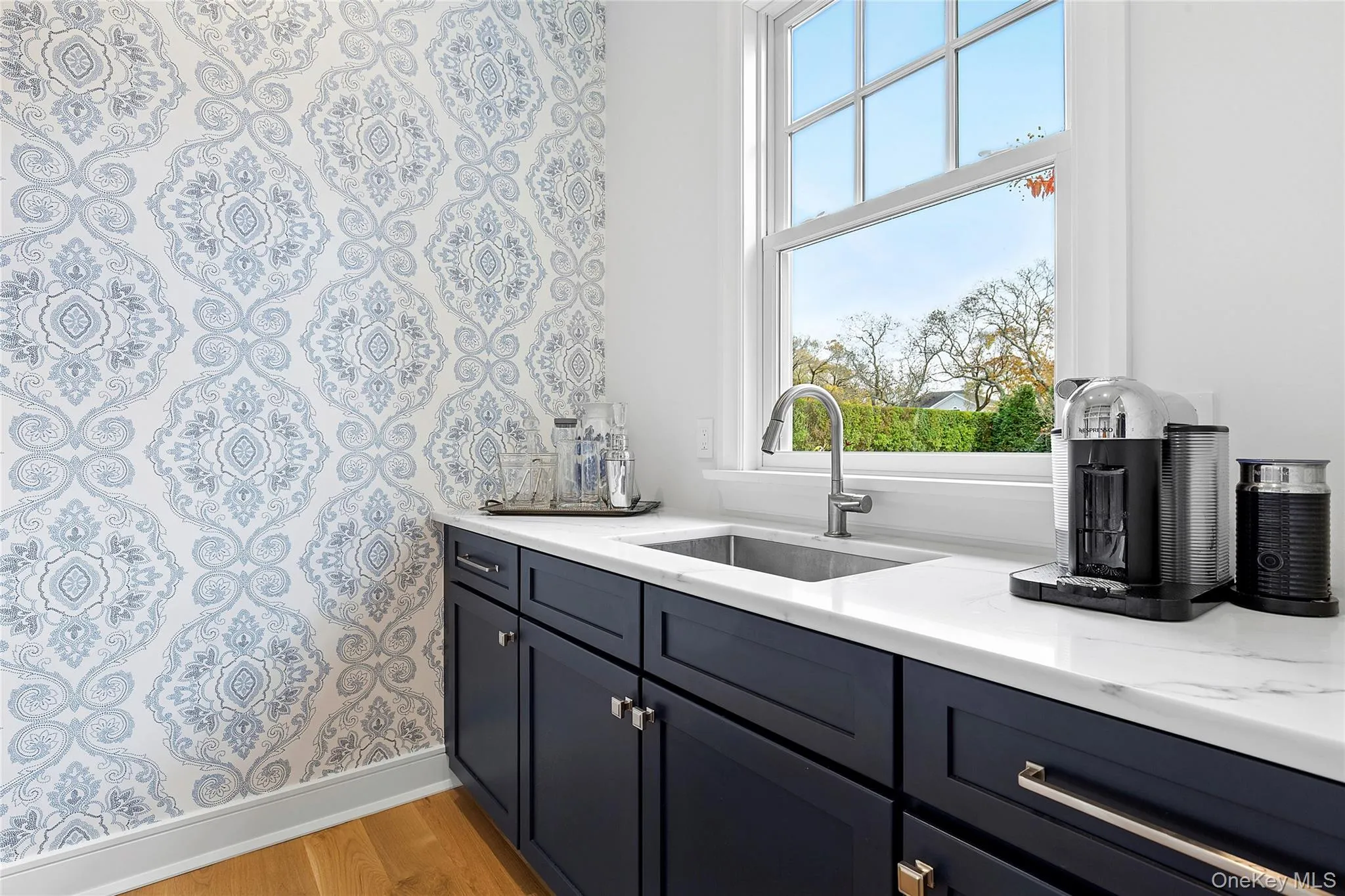 Bar area with light wood-style flooring, light stone countertops, and blue cabinetry Bar area with light wood-style flooring, light stone countertops, and blue cabinetry