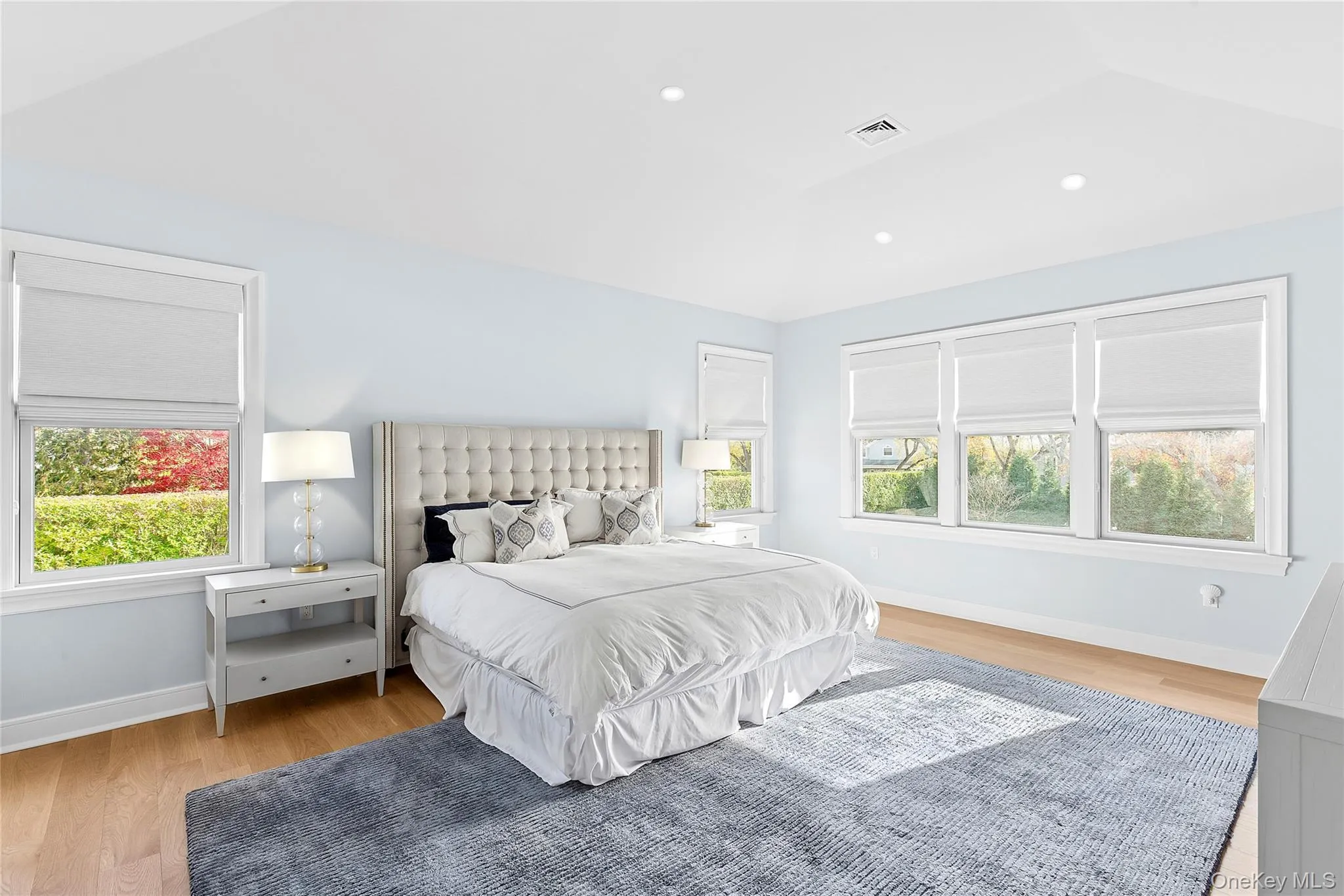 Bedroom with multiple windows, light wood-style floors, recessed lighting, and lofted ceiling Bedroom with multiple windows, light wood-style floors, recessed lighting, and lofted ceiling