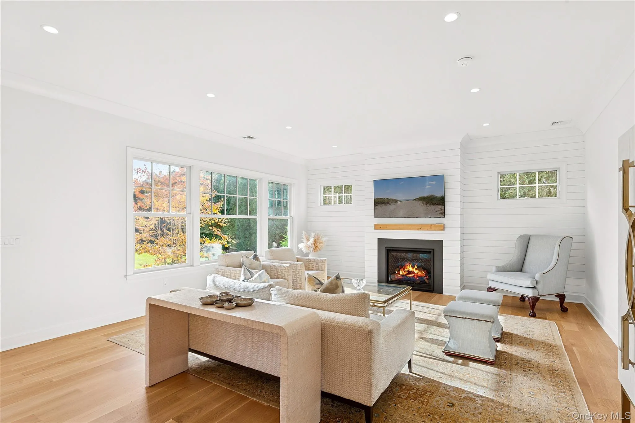 Living area featuring light wood-type flooring, crown molding, a glass covered fireplace, and recessed lighting Living area featuring light wood-type flooring, crown molding, a glass covered fireplace, and recessed lighting
