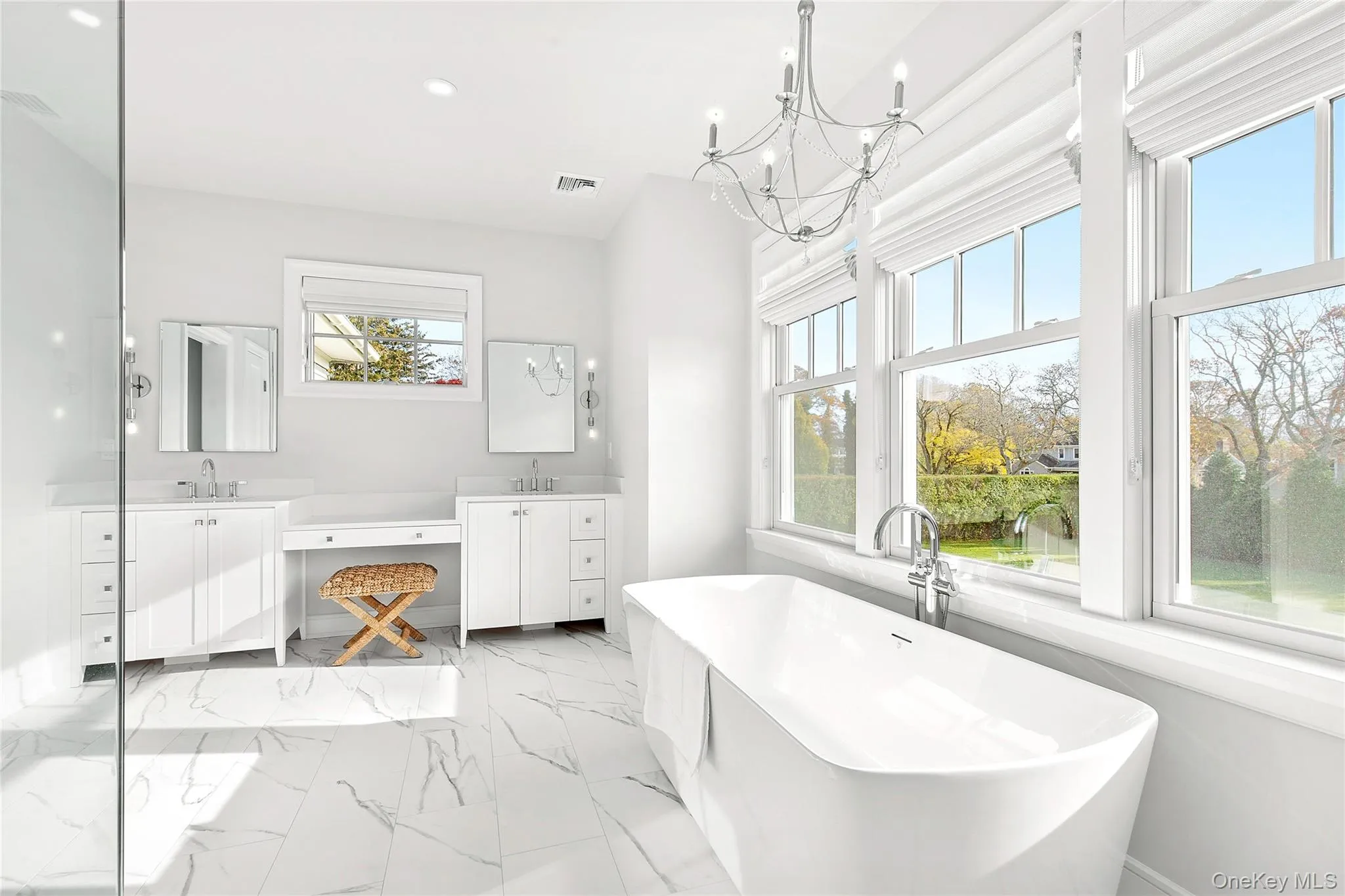 Full bathroom with double vanity, a soaking tub, light marble finish flooring, recessed lighting, and a chandelier Full bathroom with double vanity, a soaking tub, light marble finish flooring, recessed lighting, and a chandelier