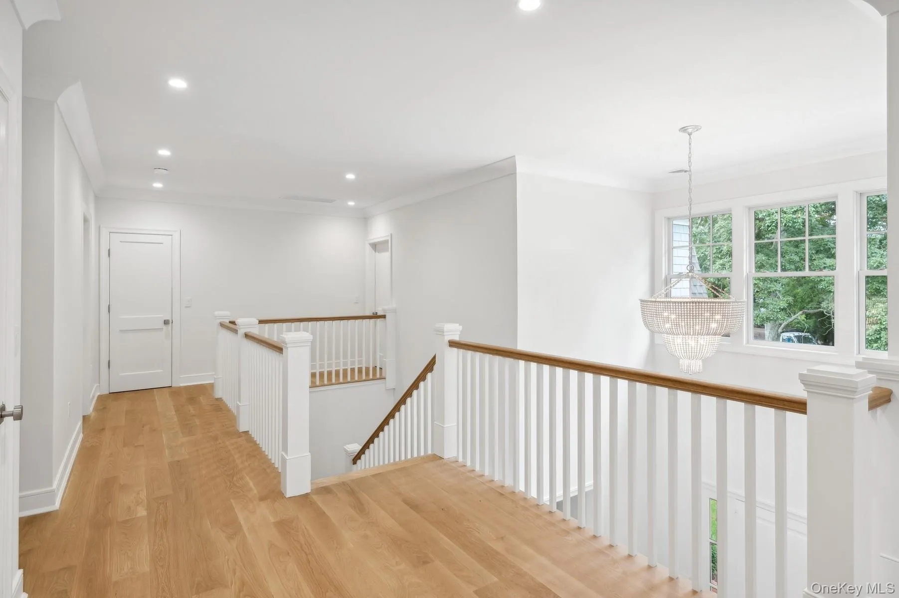 Hall with an upstairs landing, wood finished floors, recessed lighting, crown molding, and a chandelier Hall with an upstairs landing, wood finished floors, recessed lighting, crown molding, and a chandelier