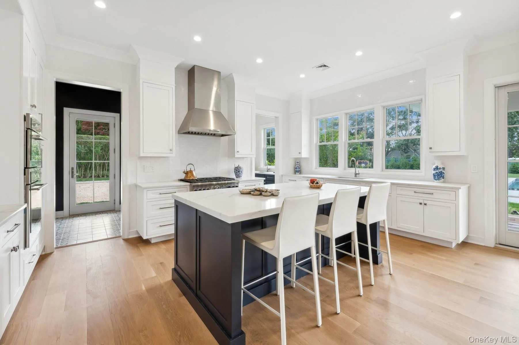 Kitchen featuring white cabinetry, a kitchen island, light wood-type flooring, recessed lighting, and light stone counters Kitchen featuring white cabinetry, a kitchen island, light wood-type flooring, recessed lighting, and light stone counters