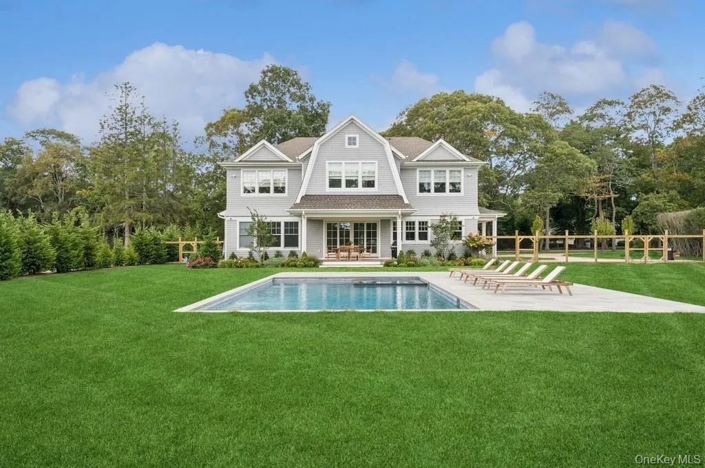 Back of house with a patio area, a gambrel roof, an outdoor pool, and view of scattered trees Back of house with a patio area, a gambrel roof, an outdoor pool, and view of scattered trees