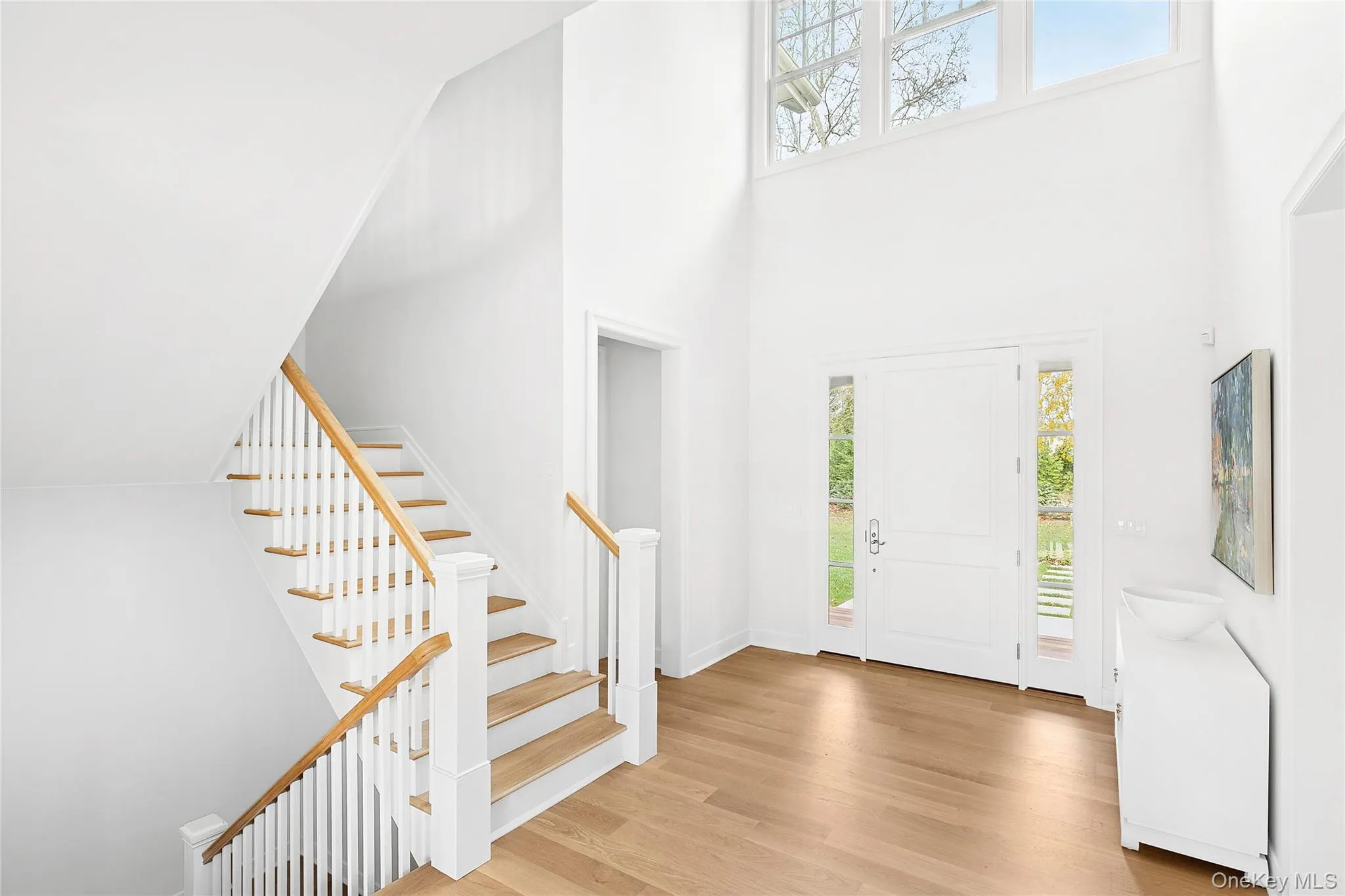 Entryway featuring light wood-type flooring, a towering ceiling, and stairs Entryway featuring light wood-type flooring, a towering ceiling, and stairs