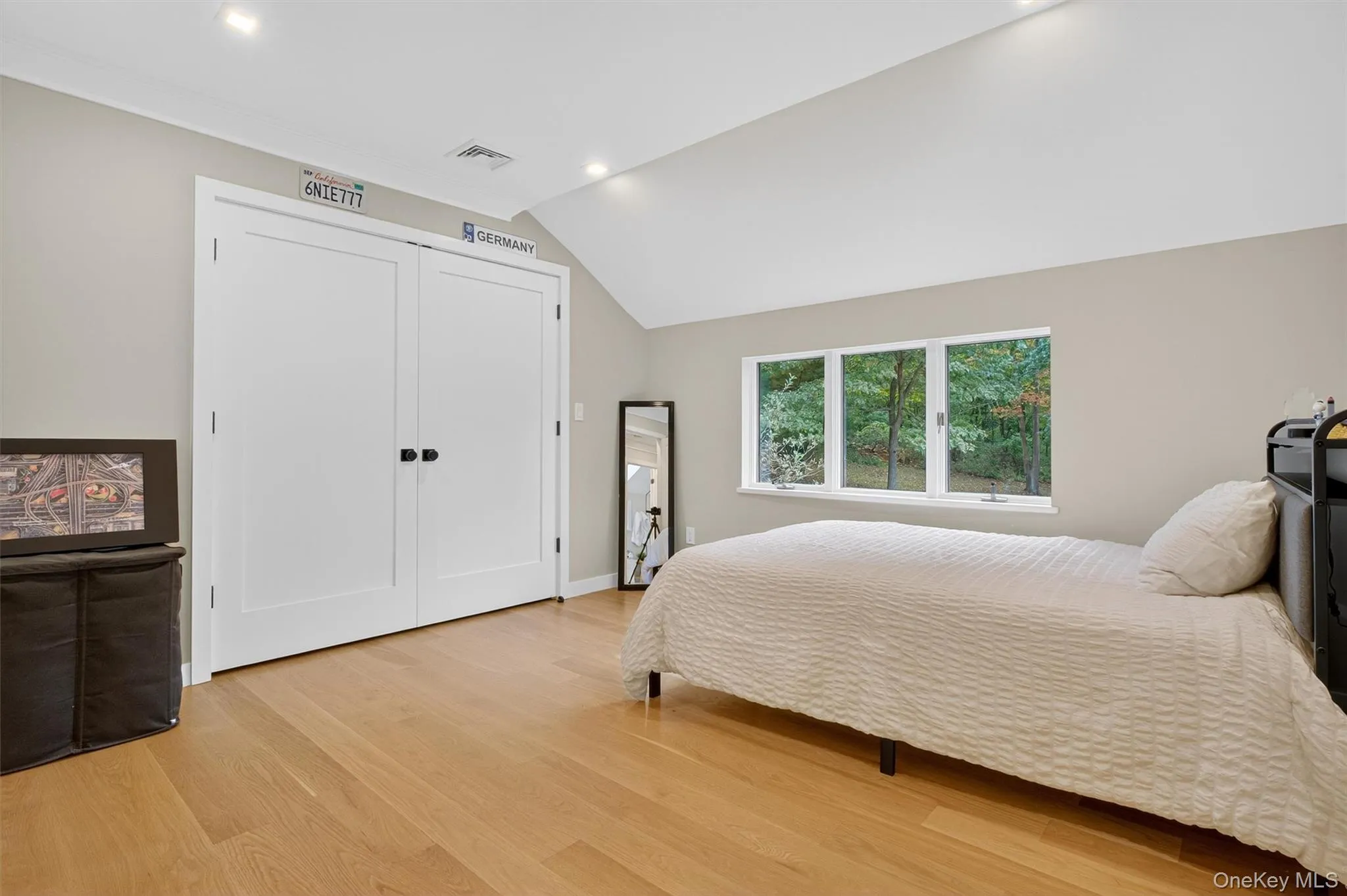 Bedroom with vaulted ceiling, recessed lighting, light wood flooring, and a closet Bedroom with vaulted ceiling, recessed lighting, light wood flooring, and a closet