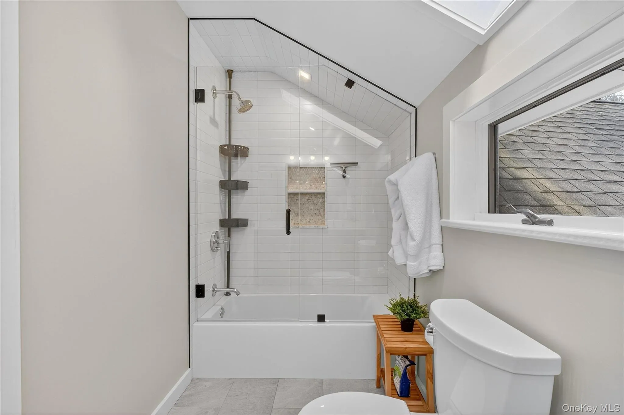 Full hall bathroom with shower / bath combination with glass door, lofted ceiling, and tile patterned floors Full hall bathroom with shower / bath combination with glass door, lofted ceiling, and tile patterned floors