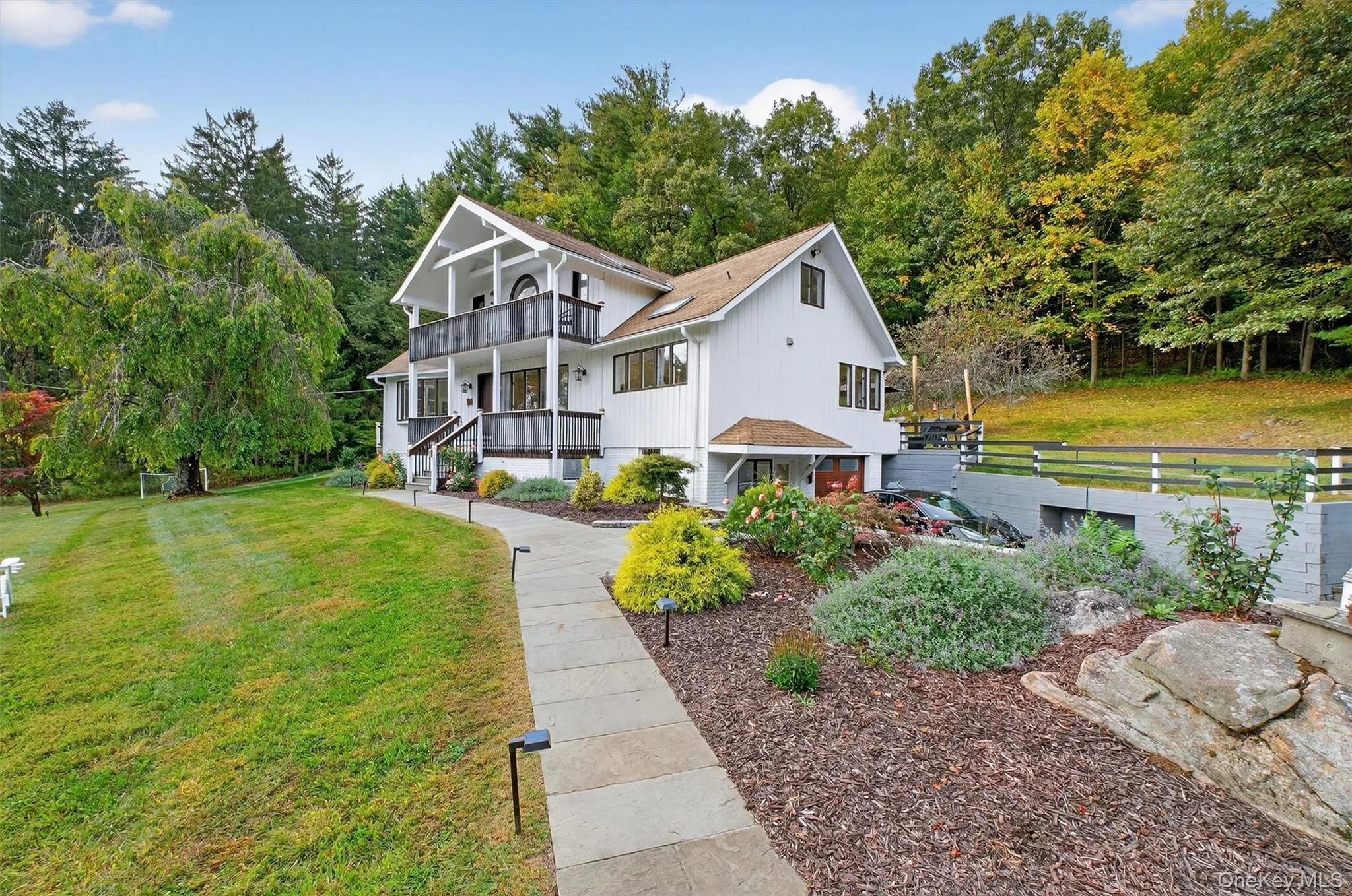 View of side of house featuring a front yard and a balcony and porch View of side of house featuring a front yard and a balcony and porch