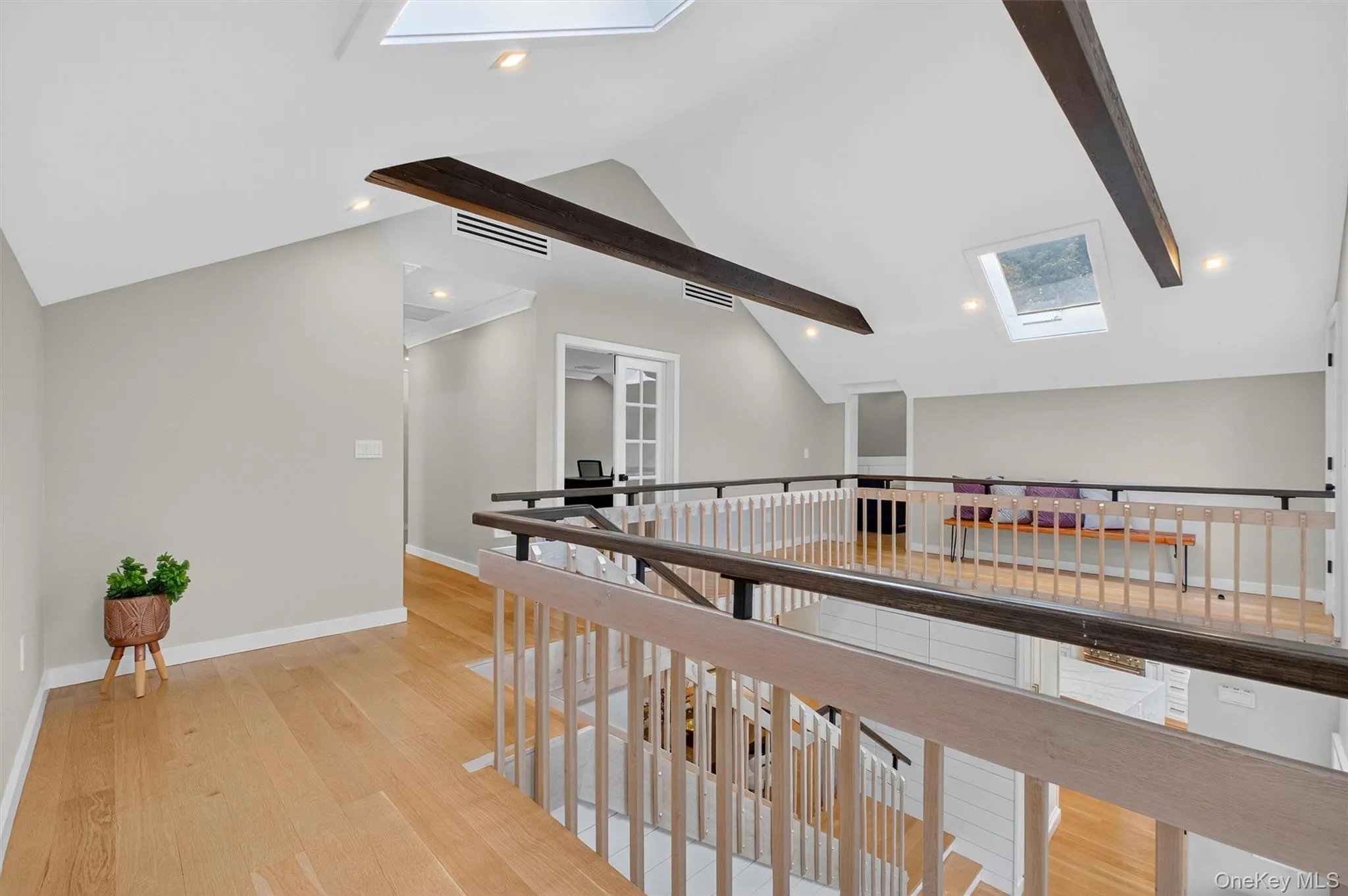 Hallway with a skylight, wood beams, light wood flooring, and recessed lighting Hallway with a skylight, wood beams, light wood flooring, and recessed lighting
