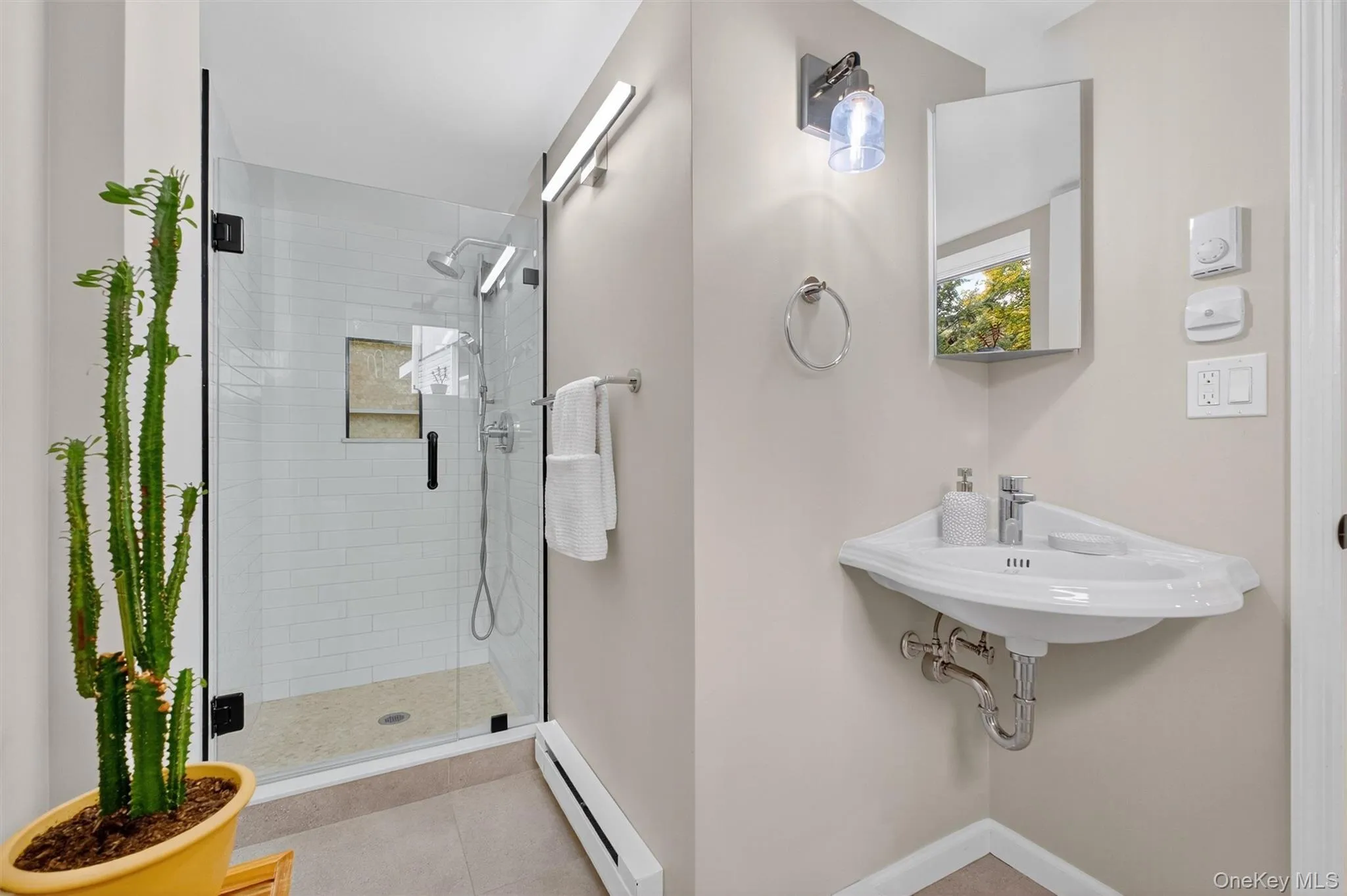 Full downstairs bathroom with a baseboard heating unit, a shower stall, and light tile patterned flooring Full downstairs bathroom with a baseboard heating unit, a shower stall, and light tile patterned flooring