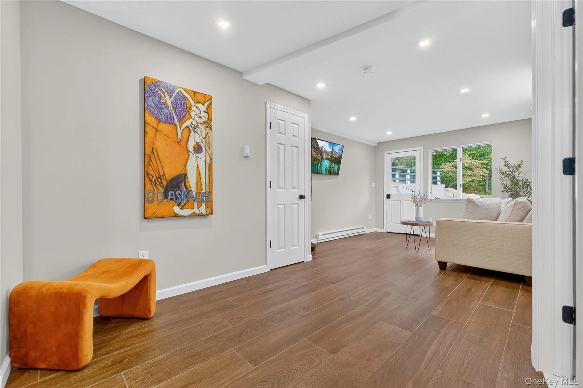 Downstairs sitting area with wood finished floors, recessed lighting, and a baseboard heating unit Downstairs sitting area with wood finished floors, recessed lighting, and a baseboard heating unit