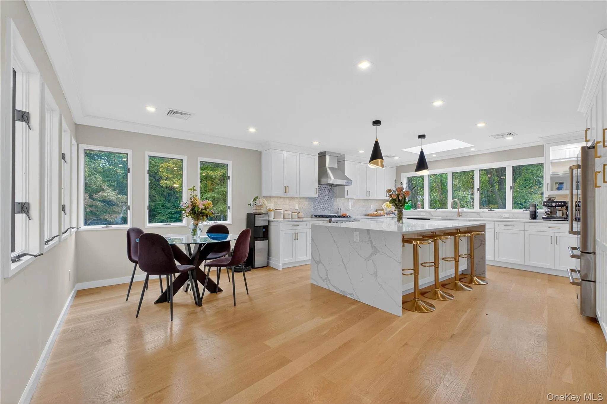 Kitchen featuring a skylight, crown molding, white cabinetry, a kitchen breakfast bar, and light stone countertops Kitchen featuring a skylight, crown molding, white cabinetry, a kitchen breakfast bar, and light stone countertops