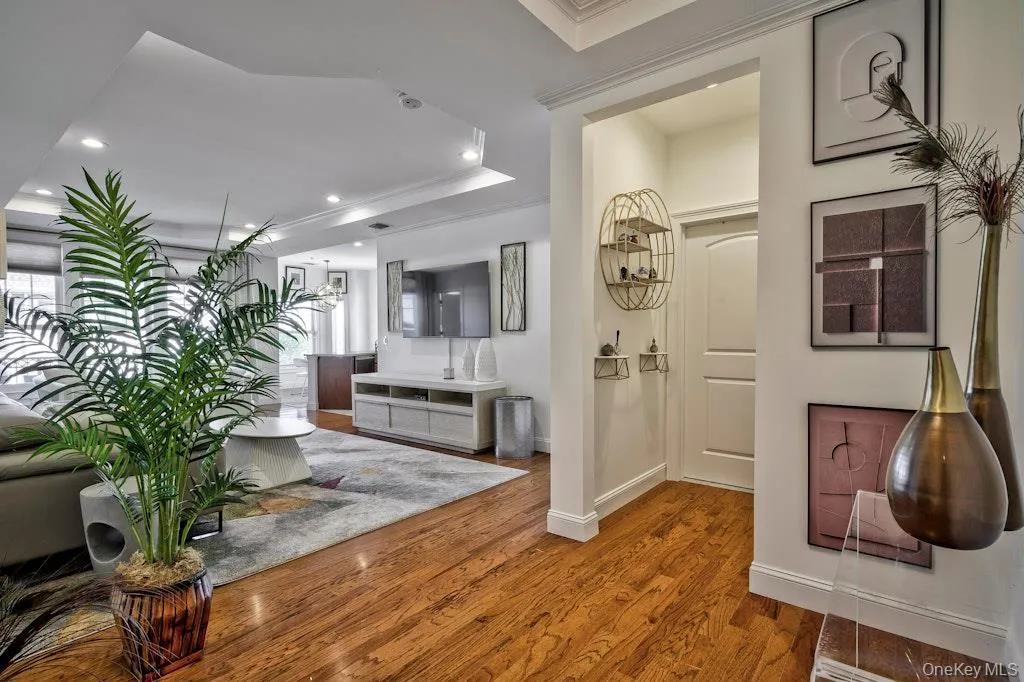 Corridor with crown molding, recessed lighting, wood finished floors, and a raised ceiling Corridor with crown molding, recessed lighting, wood finished floors, and a raised ceiling