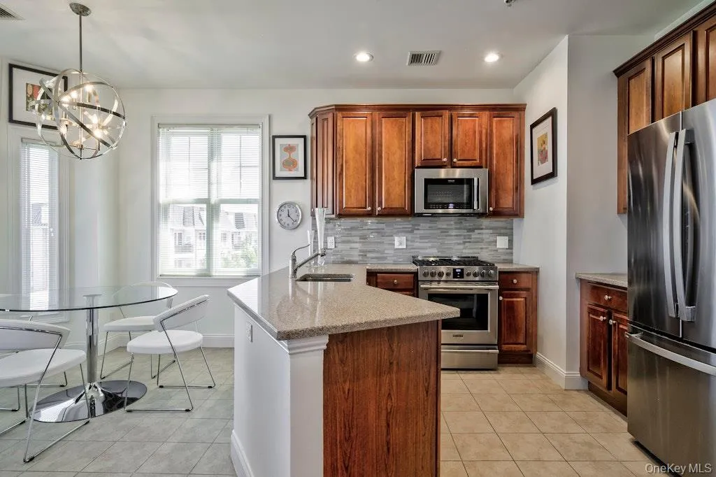 Kitchen featuring a peninsula, light tile patterned flooring, stainless steel appliances, tasteful backsplash, and recessed lighting Kitchen featuring a peninsula, light tile patterned flooring, stainless steel appliances, tasteful backsplash, and recessed lighting