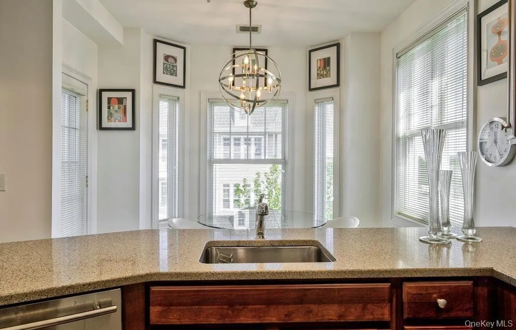 Kitchen featuring light stone counters, dishwasher, and pendant lighting Kitchen featuring light stone counters, dishwasher, and pendant lighting