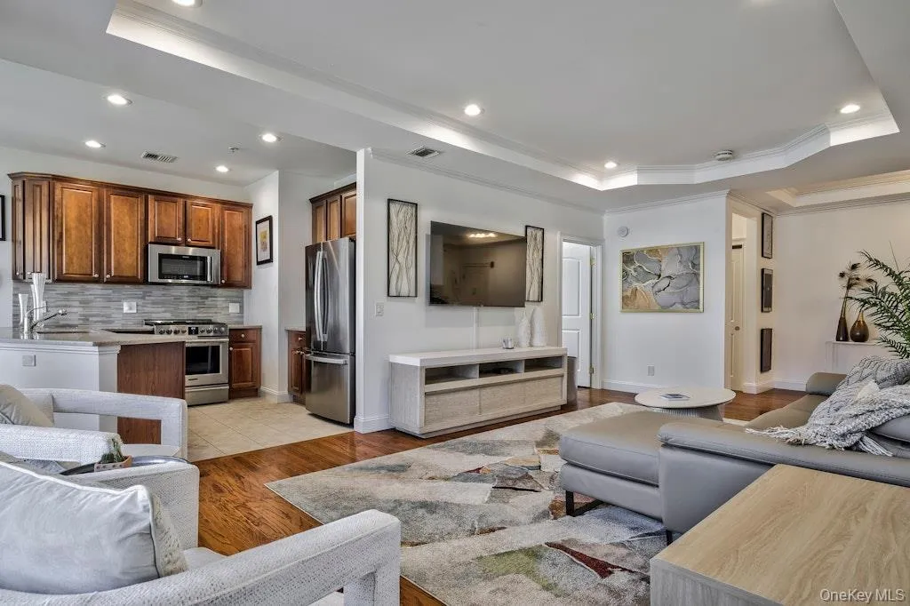 Living room with a raised ceiling, recessed lighting, light wood-style floors, and ornamental molding Living room with a raised ceiling, recessed lighting, light wood-style floors, and ornamental molding