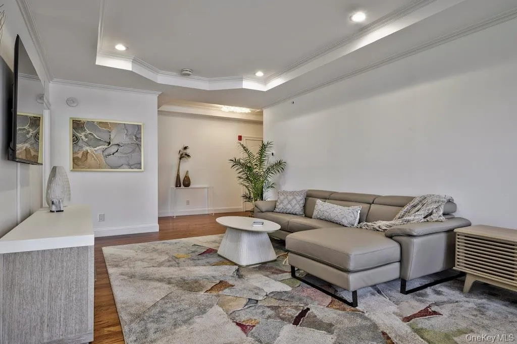 Living area with wood finished floors, recessed lighting, a tray ceiling, and ornamental molding Living area with wood finished floors, recessed lighting, a tray ceiling, and ornamental molding