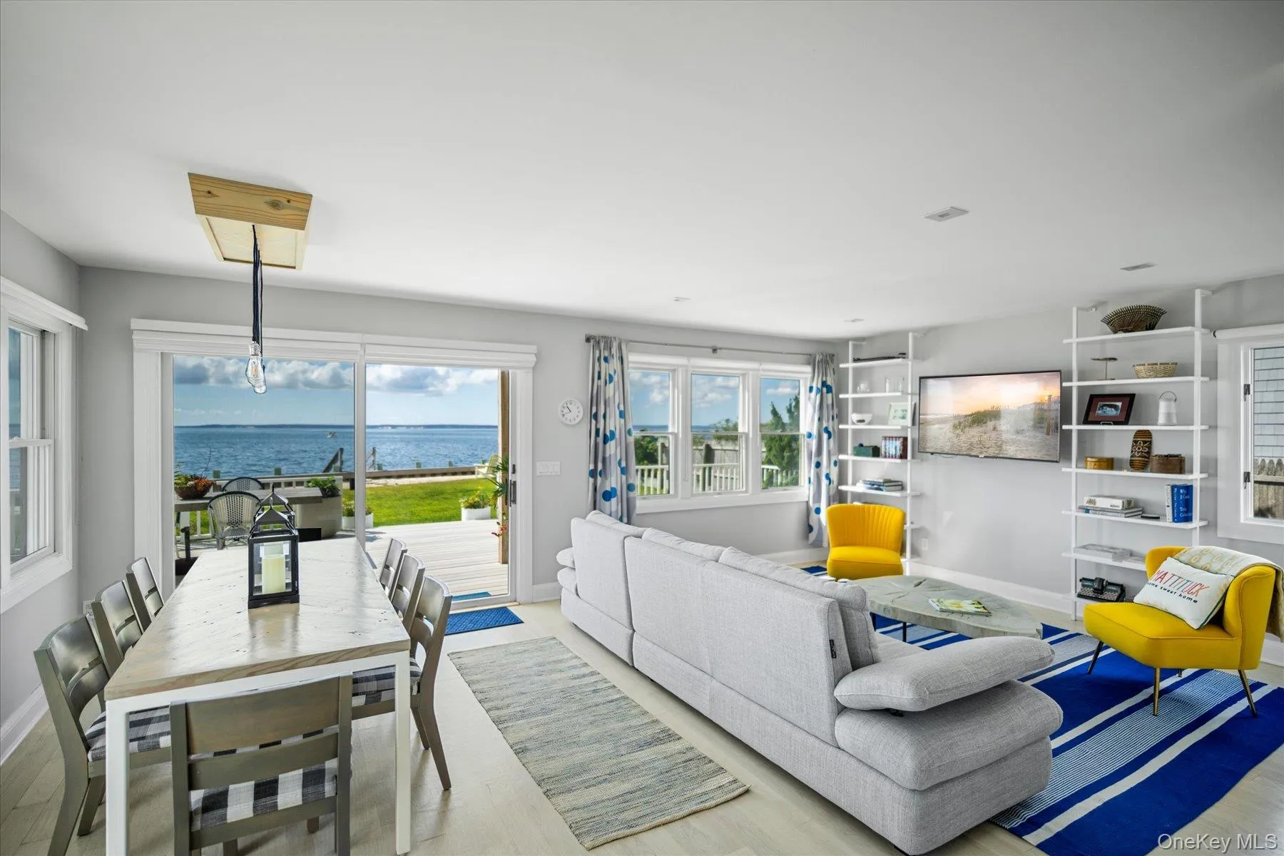 Sun filled living room with large windows and sliders framing sweeping bay views. Furnishings included in sale. Sun filled living room with large windows and sliders framing sweeping bay views. Furnishings included in sale.