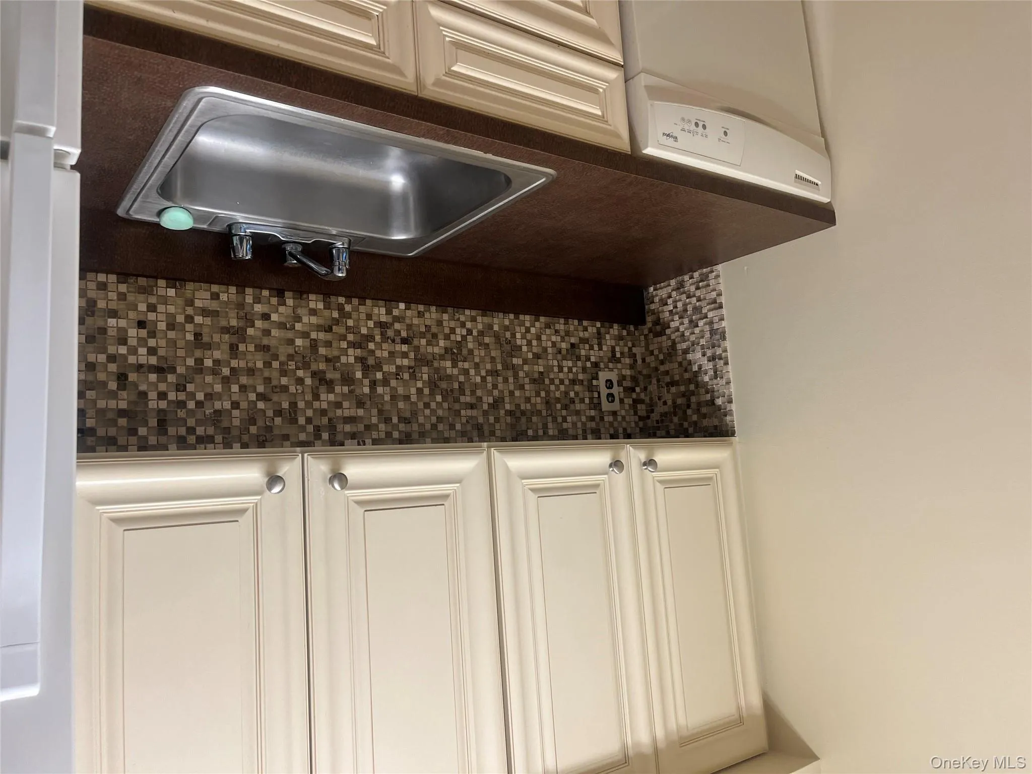 Kitchen featuring backsplash, dishwashing machine, dark countertops, and freestanding refrigerator Kitchen featuring backsplash, dishwashing machine, dark countertops, and freestanding refrigerator